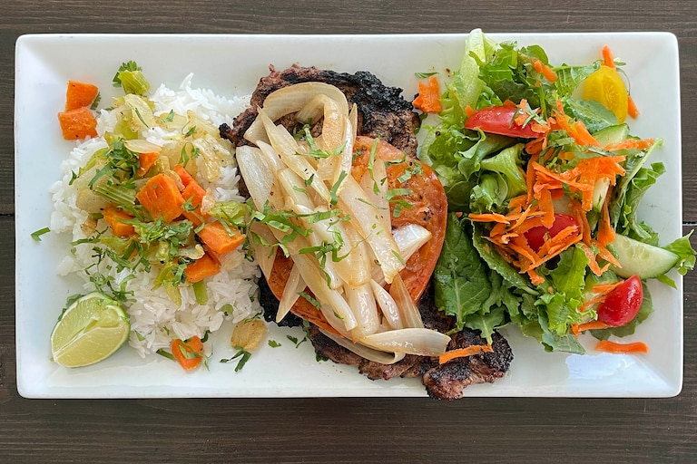 Food Runner Vilma Molina at Mera's Kitchen Collective brings El Salvadoran Bistec Encebolladas, a celebratory dish of grilled steak and marinated vegetables, to the restaurant's menu starting March 24.