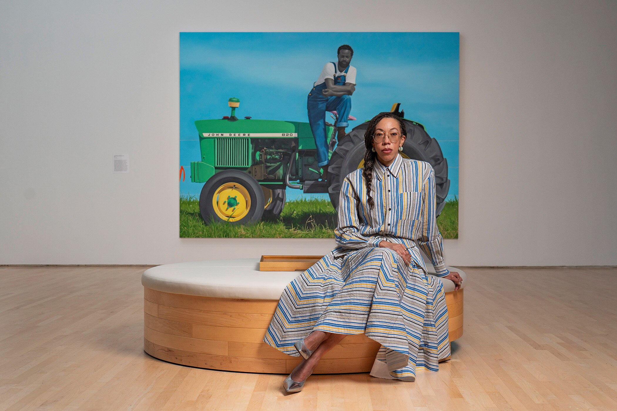 Amy Sherald, seated in front of her piece "A God Blessed Land (Empire of Dirt)."