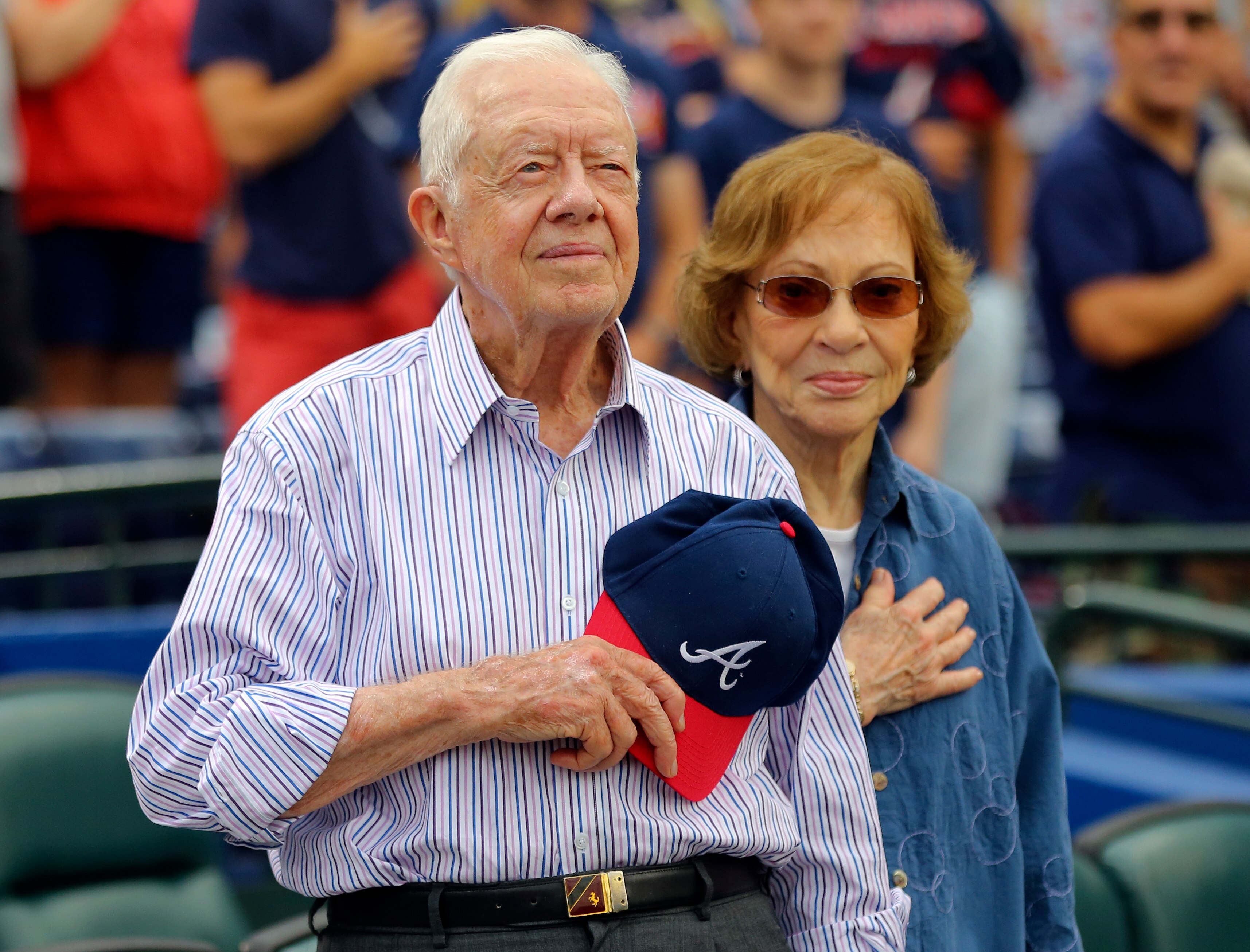 Former President Jimmy Carter and his wife, Rosalynn, stand for the national anthem before a baseball game between the Atlanta Braves and the San Diego Padres, June 10, 2015, in Atlanta.