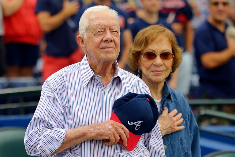 Former President Jimmy Carter and his wife, Rosalynn, stand for the national anthem before a baseball game between the Atlanta Braves and the San Diego Padres, June 10, 2015, in Atlanta.