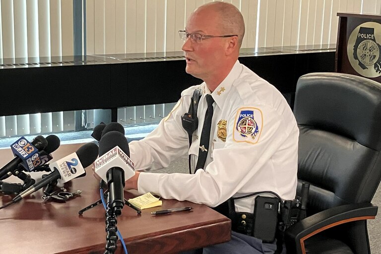 Dennis Delp, interim police chief for Baltimore County, sits at a table. Several microphones are placed on the table and point towards him.