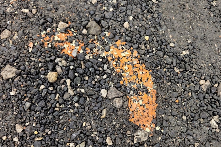 A detail showing paint chips on the ground under the W. 28th Street overpass.