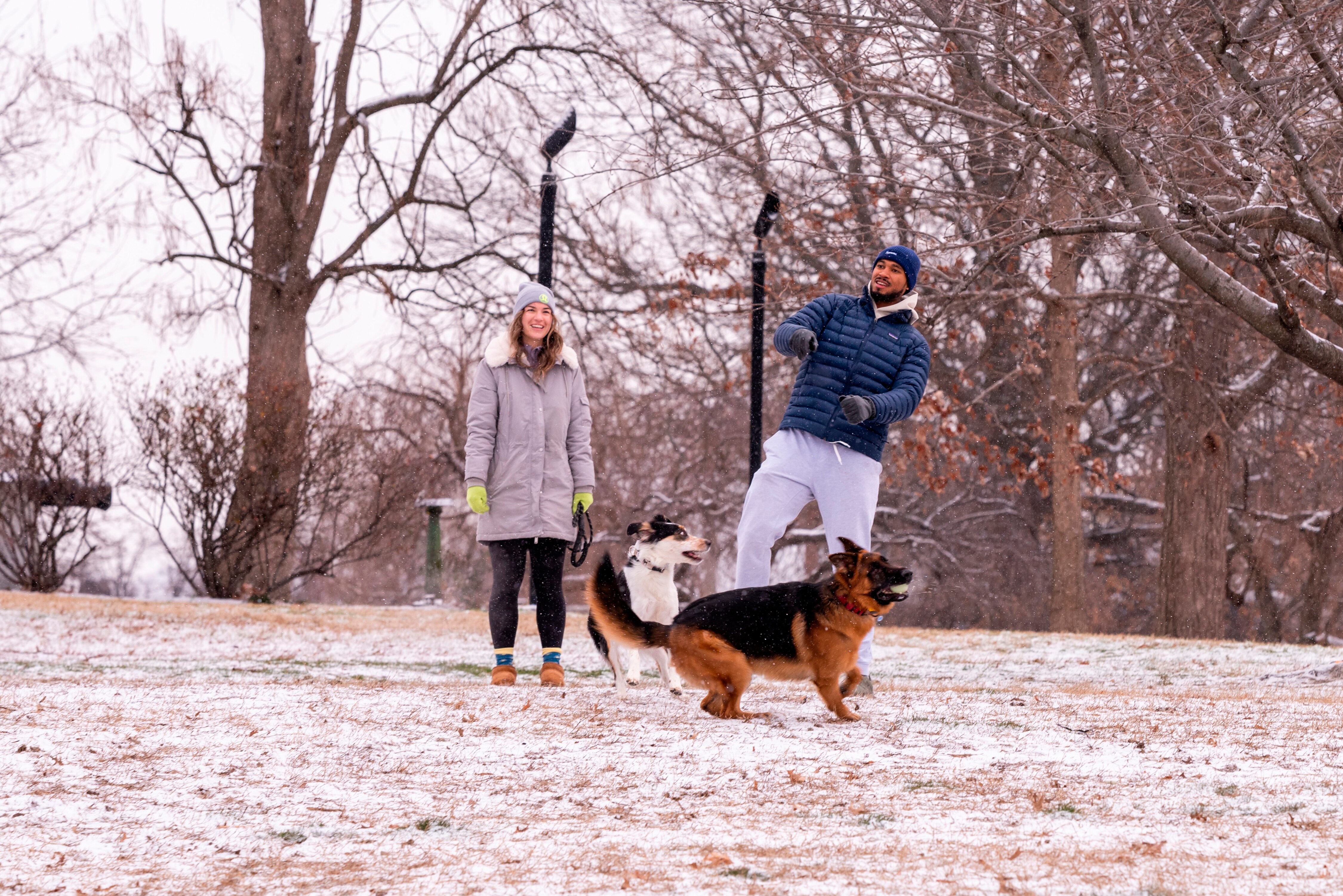 Emily Wheeler, left, and Jarred Thomas, play fetch with their dog Marlo (black and white) in Riverside Park, Baltimore, Maryland.