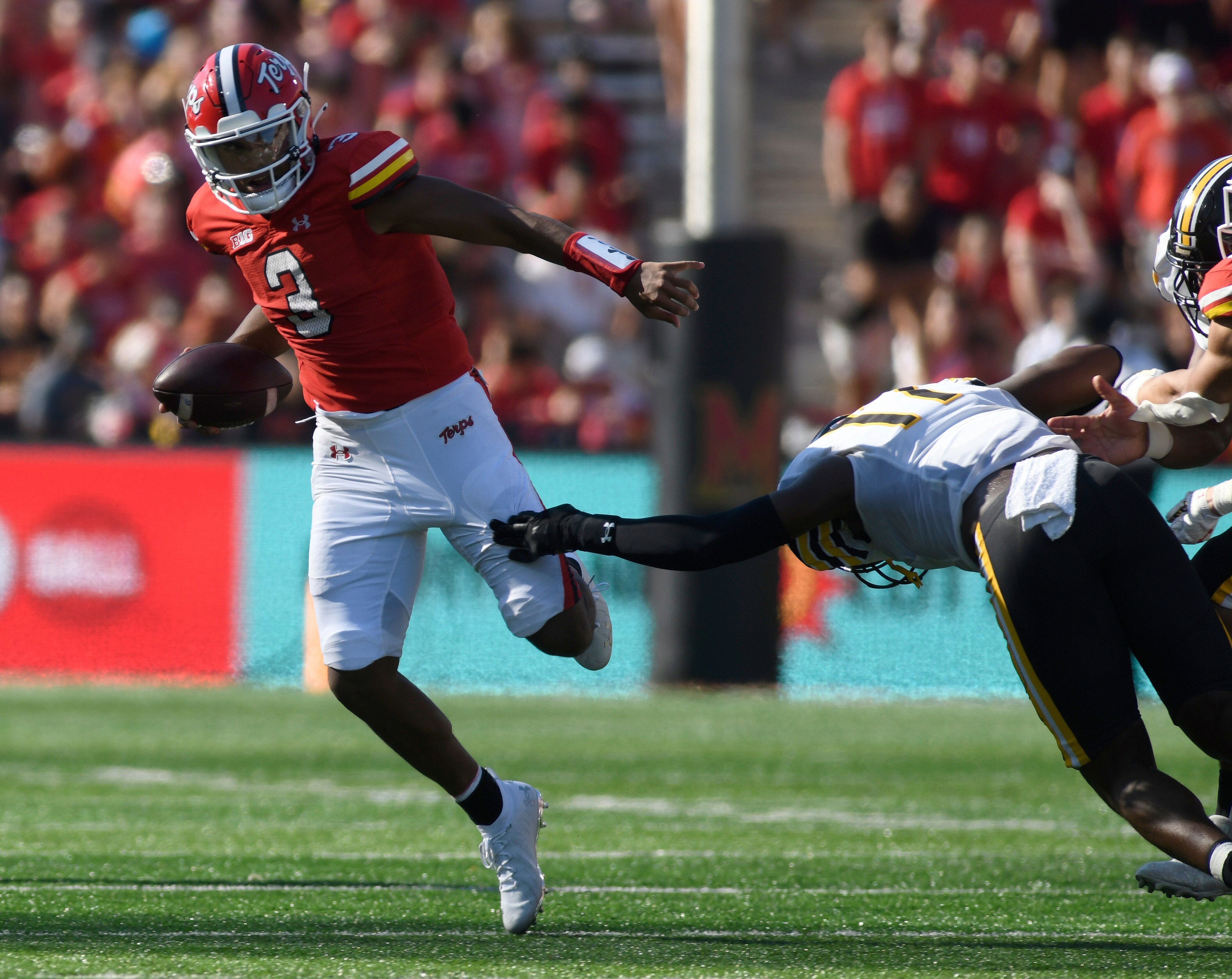 Maryland quarterback Taulia Tagovailoa escapes the tackle of Towson defensive lineman Olyfride Okombi in the first half Saturday in College Park.