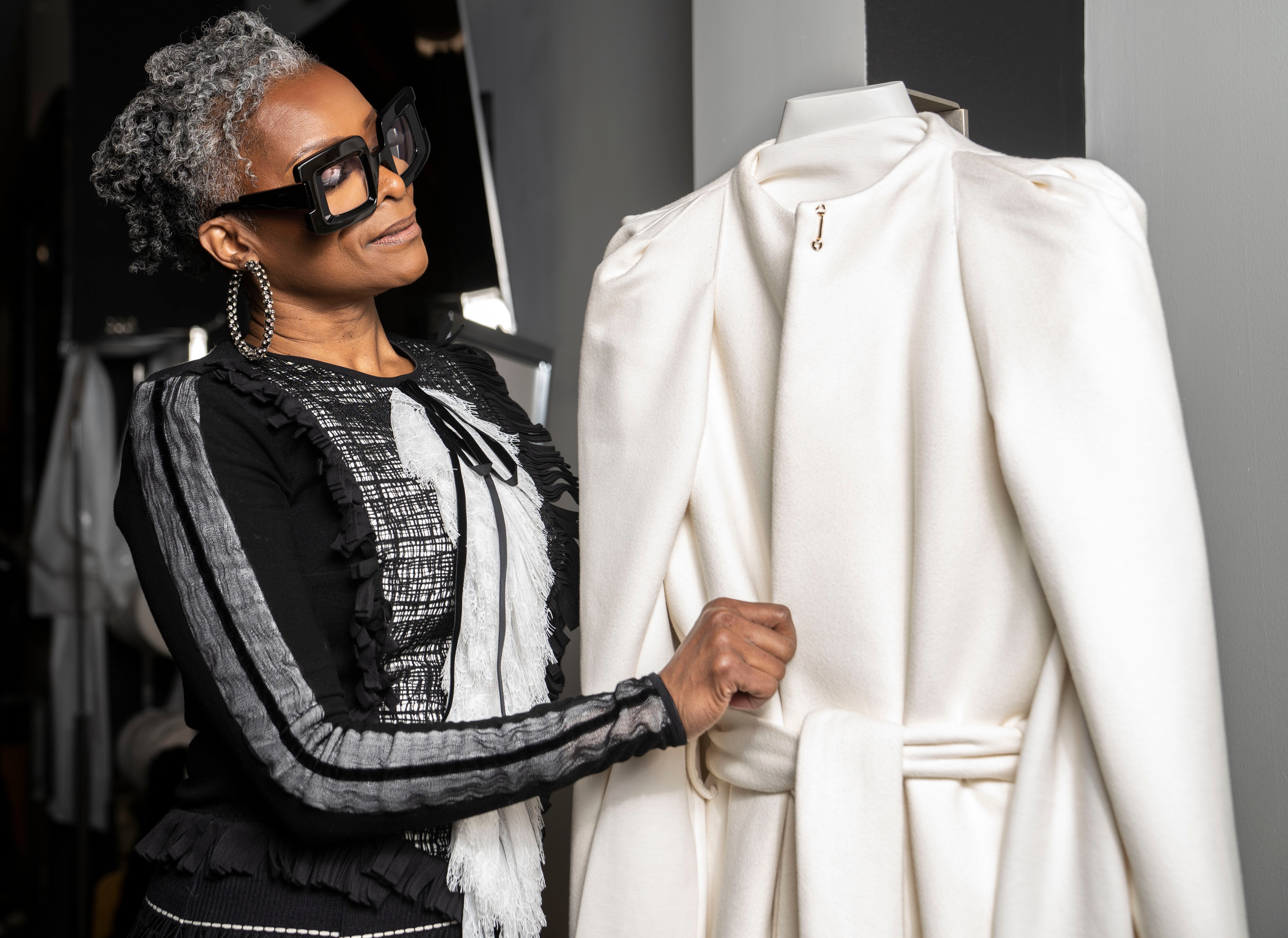Jody Davis poses for a portrait next to white ensemble worn by First Lady Dawn Moore at the swearing in ceremony of her husband, Governor Wes Moore, at Jody Davis Designs in Baltimore, Saturday, March 4, 2023.