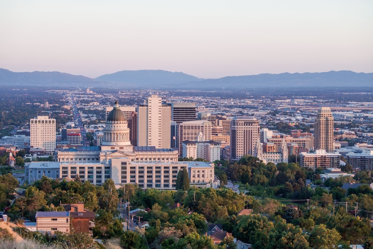 Salt Lake City, Utah - July 20, 2019: Salt Lake City skyline with Utah State Capitol in the foreground and Wasatch mountain range in the background in the clear summer evening sunset sky
