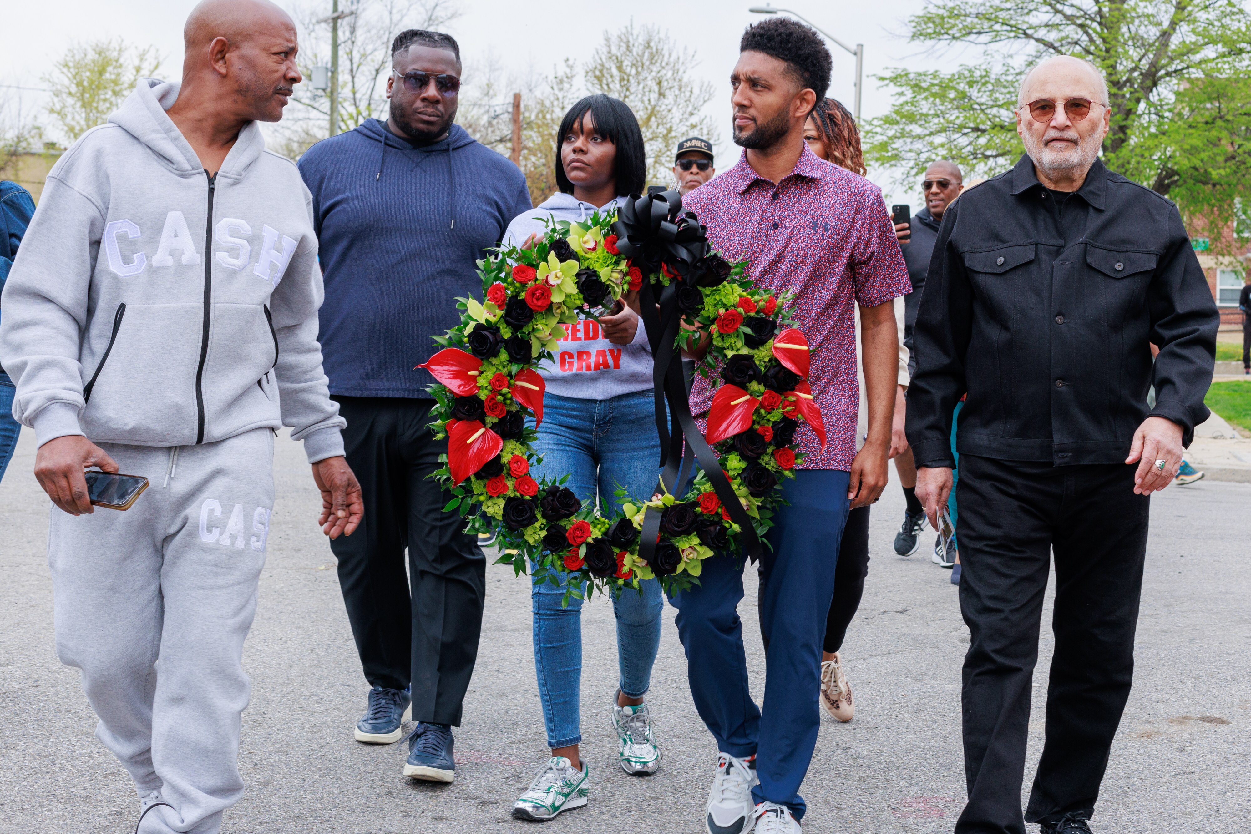 Mayor Brandon Scott, attorney William H. “Billy” Murphy Jr. and Fredricka Gray carry a memorial wreath to place at a mural of Freddie Gray in the Sandtown-Winchester neighborhood on Saturday.