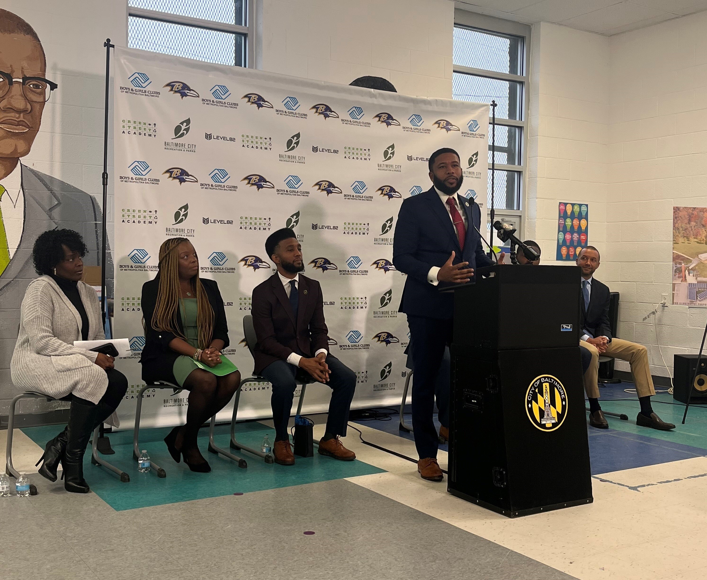 (Left to right) President of Carrollton Manor Neighborhood Improvement Association Pamela Green, Executive Director of Green Street Academy Denisha Logan, Mayor Brandon Scott, Board Chair of the Boys & Girls Club of Metropolitan Baltimore Nik Tatum, LEVEL82 Co-founder and former Baltimore Raven Torrey Smith, and President of the Baltimore Ravens Sashi Brown speak at an event announcing a $20 million commitment to create Baltimore Ravens Boys & Girls Club at Hilton Recreation Center.
