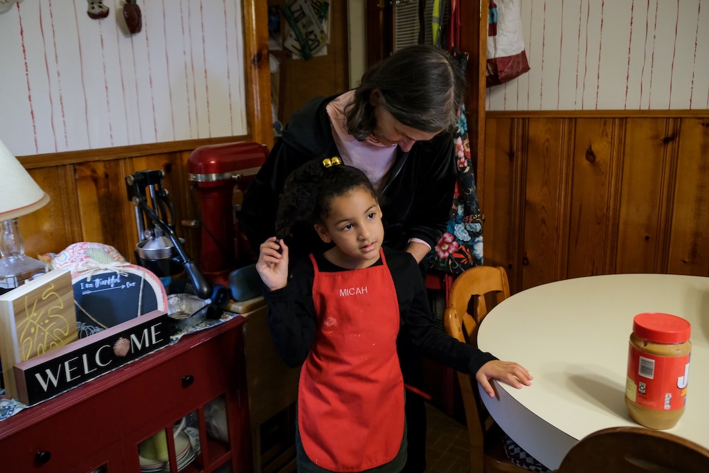 Beth Rannie ties an apron on her granddaughter, Micah Walker, before starting on the family tradition of “cookie day” — baking pizzelles for Thanksgiving.