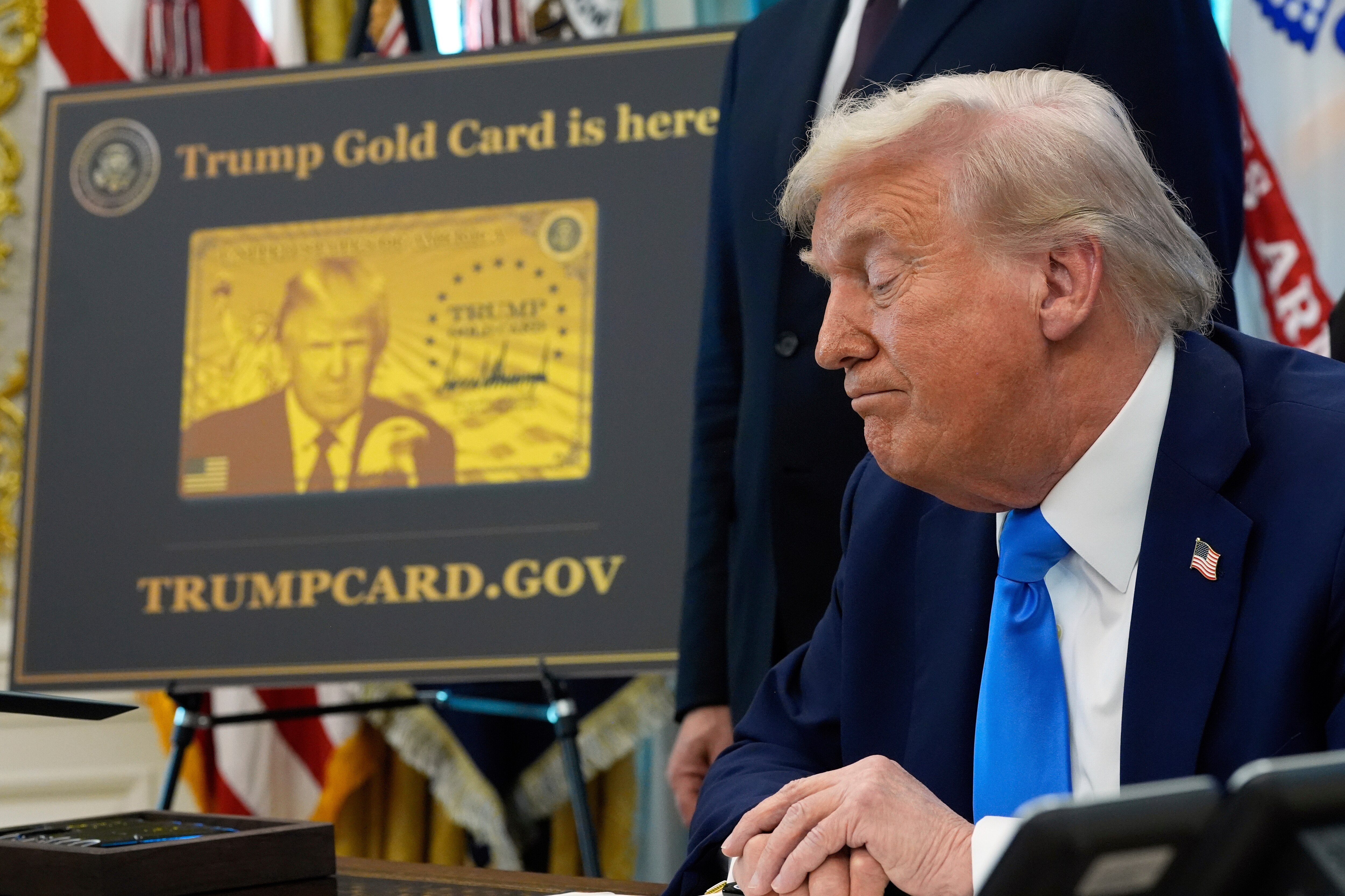 FILE - A poster showing the Trump Gold Card is seen as President Donald Trump signs executive orders in the Oval Office of the White House, Sept. 19, 2025, in Washington. (AP Photo/Alex Brandon, file)