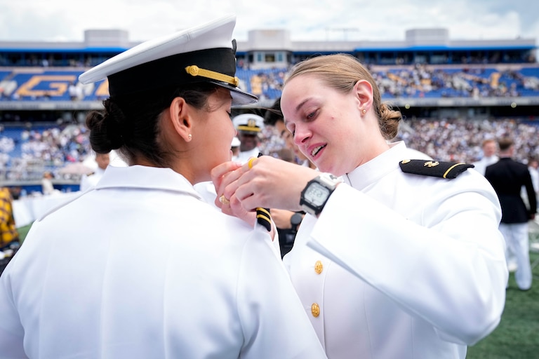 Midshipman Jenna Jeletic, right, puts the shoulder boards on her friend, newly commissioned naval officer Arianna Longo, following the U.S. Naval Academy Class of 2025’s graduation ceremony at the Navy-Marine Corps Memorial Stadium in Annapolis, Md. on Friday, May 23, 2025.