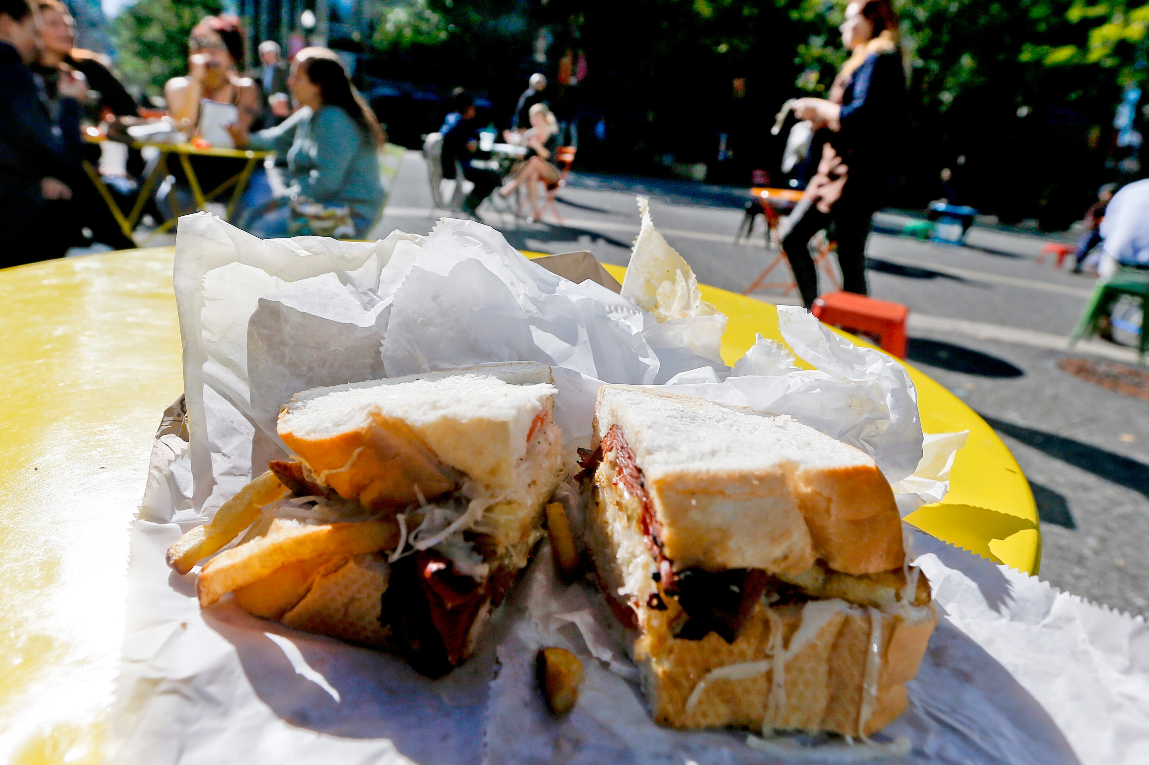 A Primanti Bros. sandwich with pastrami, french fries and cole slaw is sliced open on one of the tables in Market Square in downtown Pittsburgh.