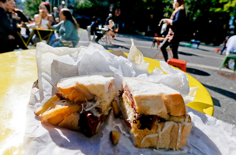 A Primanti Bros. sandwich with pastrami, french fries and cole slaw is sliced open on one of the tables in Market Square in downtown Pittsburgh.