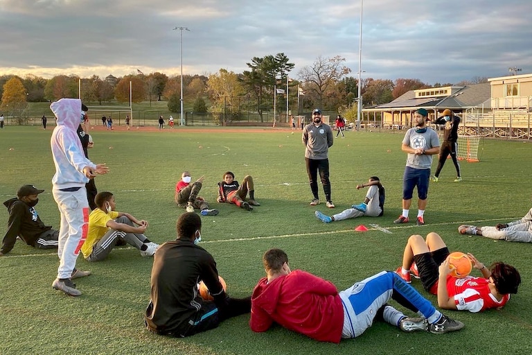 Warshan Hussin (center) stands and smiles as his team lays on the ground following practice.
