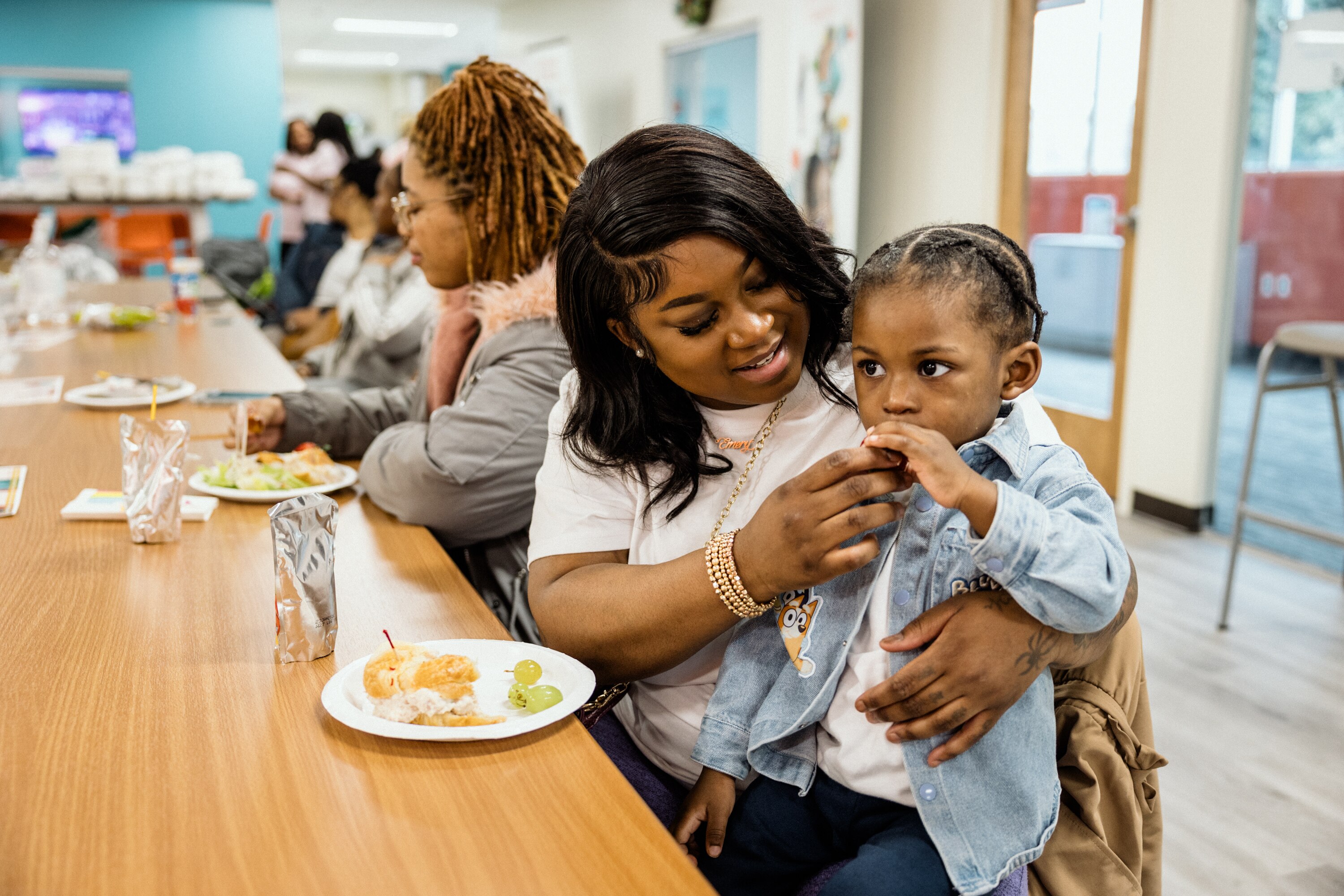 BALTIMORE, MD - March 16, 2025: Emma Artis, 26, and her son, Emery, 1, have a snack in the lobby of the Jeremiah Program on March 16, 2025. The Jeremiah Program Baltimore, Charm City Pearls Foundation, Inc. and Esi's House have partnered together to host a yoga wellness event to support single mothers.
