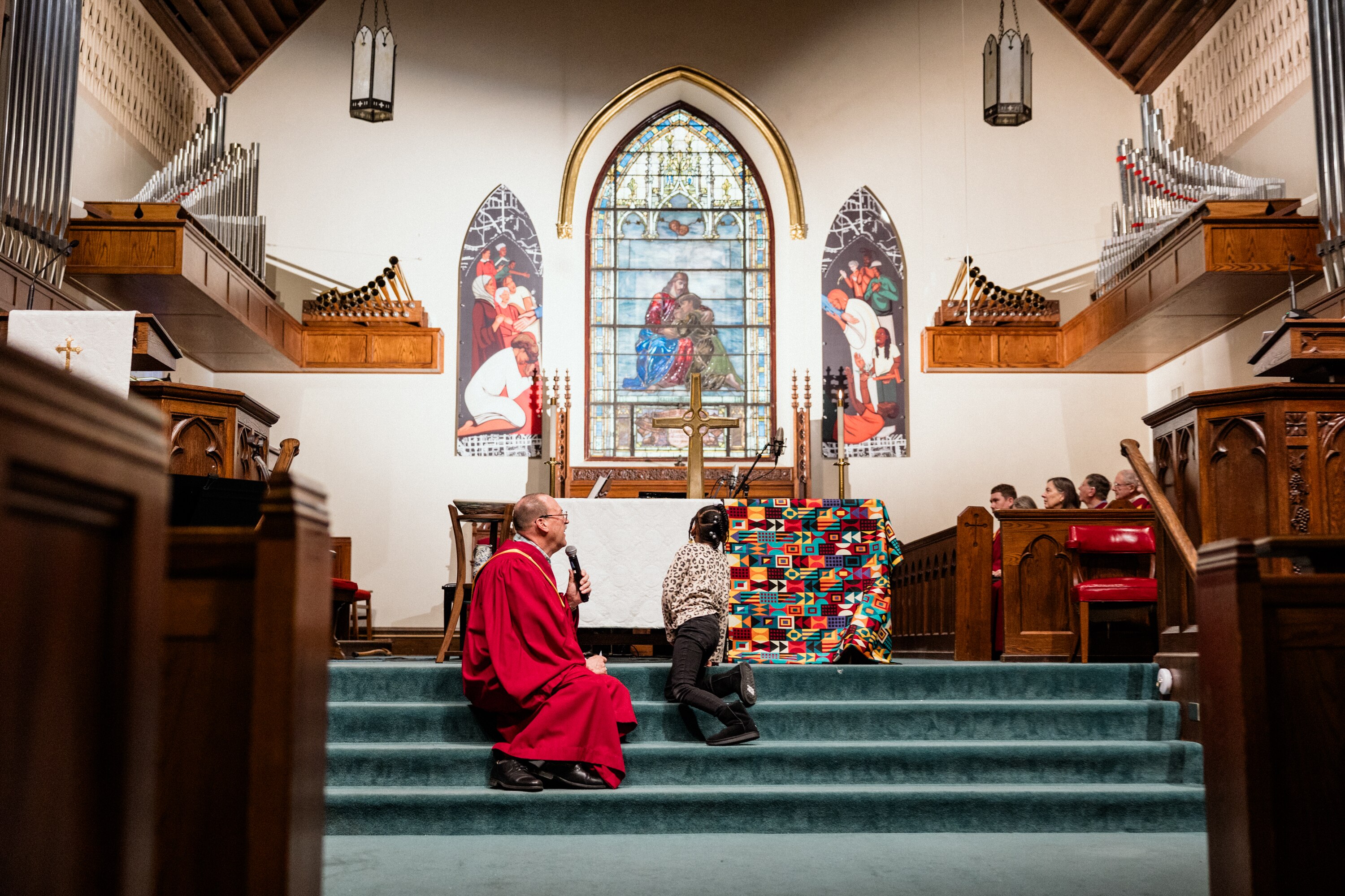 BALTIMORE, MD - FEB 9, 2025: Doug Storey facilitates a children’s sermon acknowledging the lack of diverse representation in imagery inside the Govans Presbyterian Church. He asks one of the child attendees to look at the new artwork titled "Sanctuary City Part 1 and 2” that represents the growing diversity and representation of their congregation where everyone is welcome.