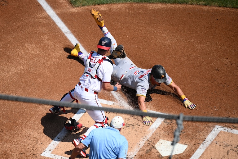 Pittsburgh Pirates' Konnor Griffin, right, steals home to score against Washington Nationals catcher Drew Millas, left, during the first inning.