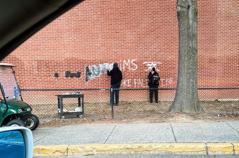 A neighbor driving by photographed anti-Muslim and anti-Palestinian graffiti being cleaned off a wall at Walt Whitman High School in Bethesda on Friday.