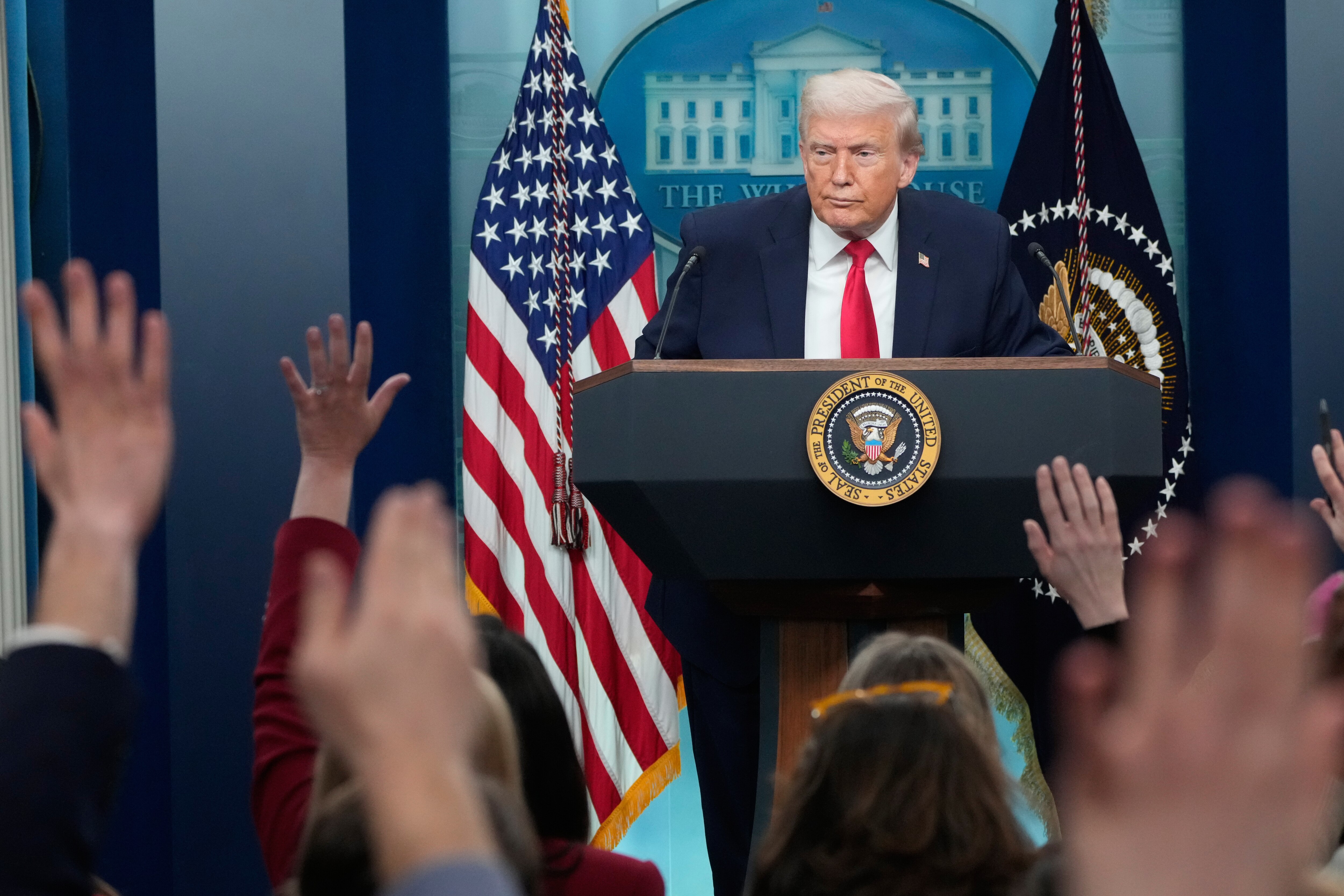 Reporters raise their hands as President Donald Trump speaks during a press briefing at the White House in Washington, Tuesday, Jan. 20, 2026.