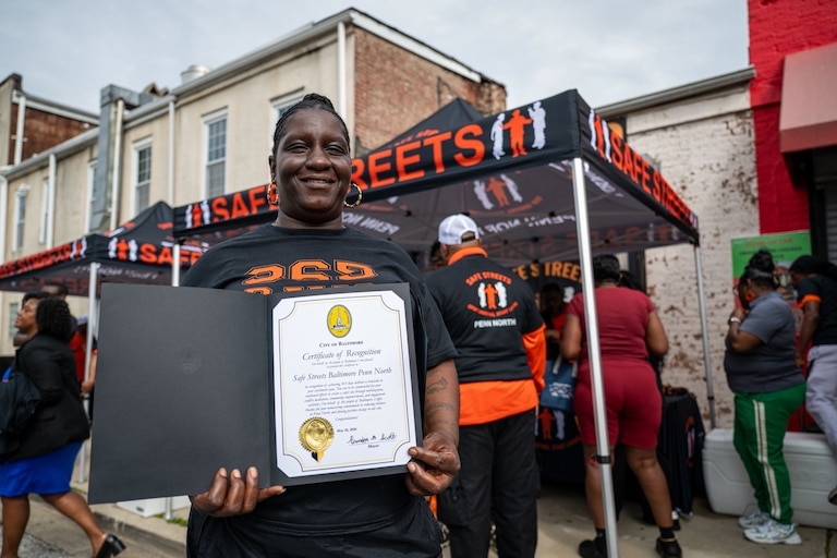 Rochelle Johnson, site director for Safe Streets Penn North, holds a certificate from Mayor Brandon Scott celebrating a year without a homicide in the community.