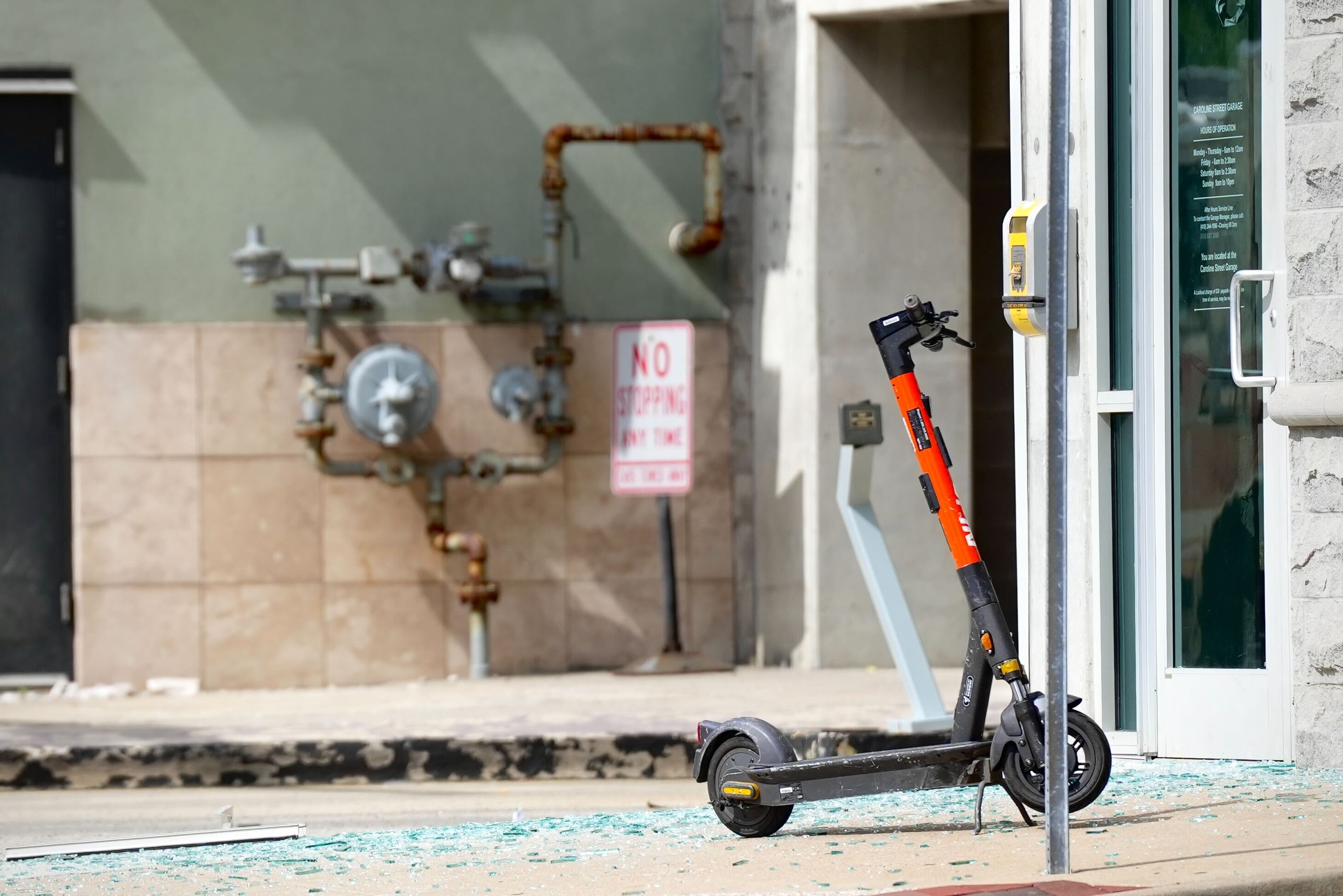 Glass shards cover the ground near an abandoned electric scooter outside of the Caroline Street garage where an explosion occurred Wednesday afternoon in Fells Point.