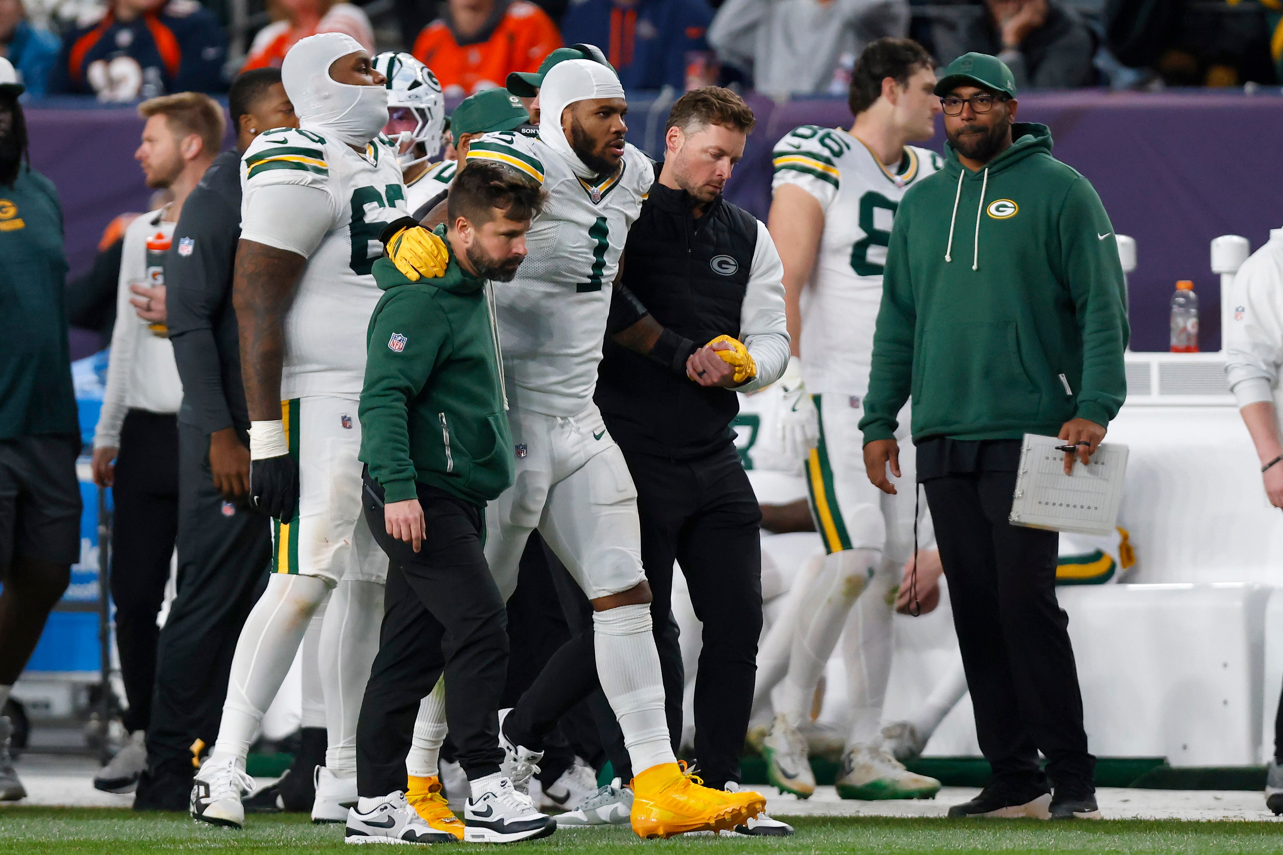 Micah Parsons of the Packers leaves the field after injuring his left knee Sunday in Denver.