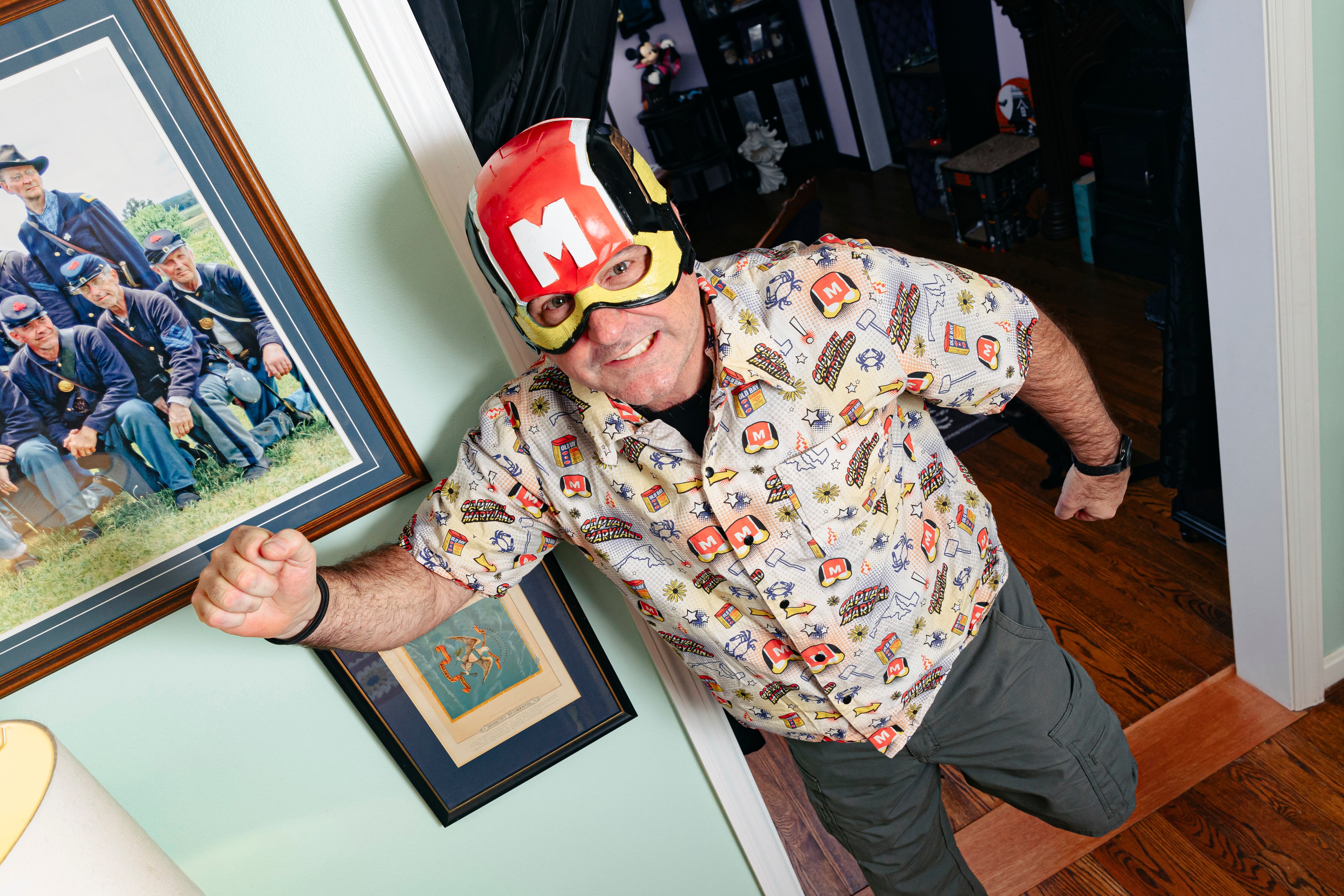 Clark Oliver, also known as Captain Maryland, wears his alter ego’s helmet surrounded by memorabilia from decades of being a costume and sci-fi enthusiast at his home on Wednesday, Dec. 6, 2023. (Wesley Lapointe/for The Baltimore Banner)
