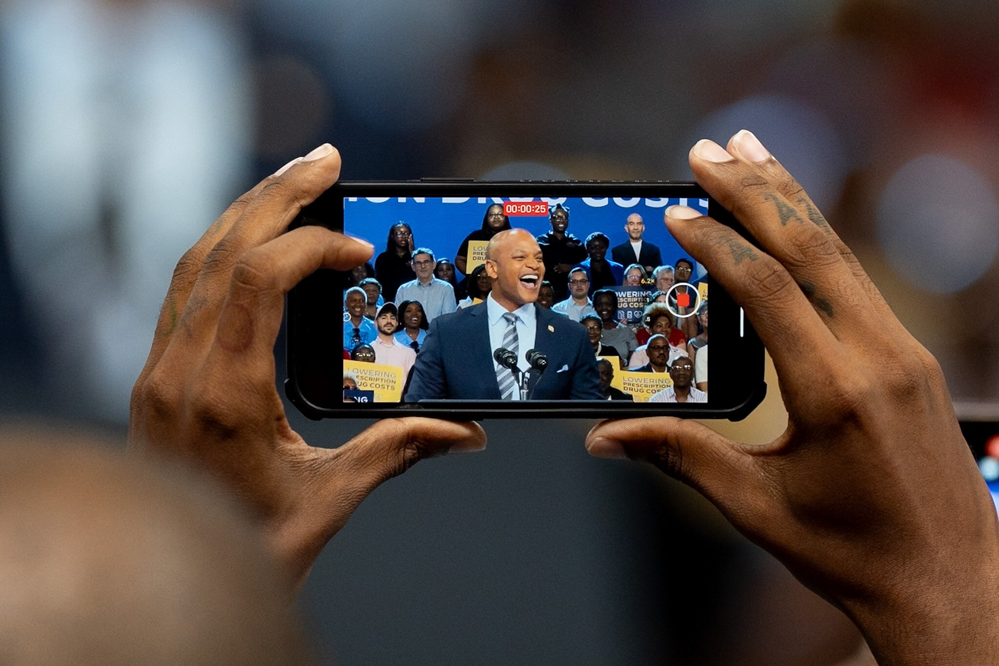 An attendee films as Maryland Gov. Wes Moore speaks during a Biden/Harris administration event at Prince George’s Community College on Aug. 15, 2024.