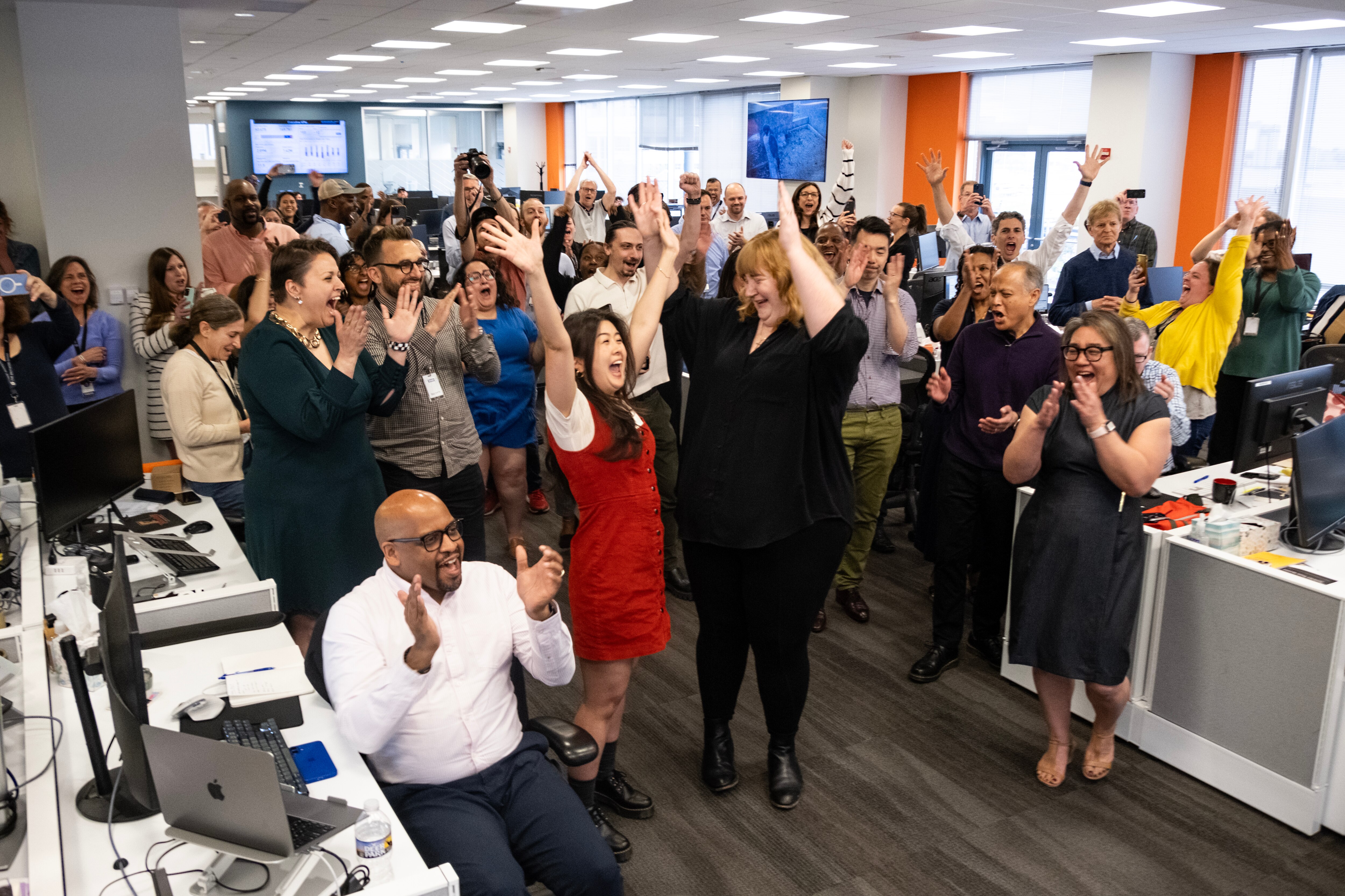 Reporter Alissa Zhu, center left, and photojournalist Jessica Gallagher, center right, celebrate with the Baltimore Banner newsroom as they find out they've won the Pulitzer Prize for Local Reporting on Monday, May 5, 2025.