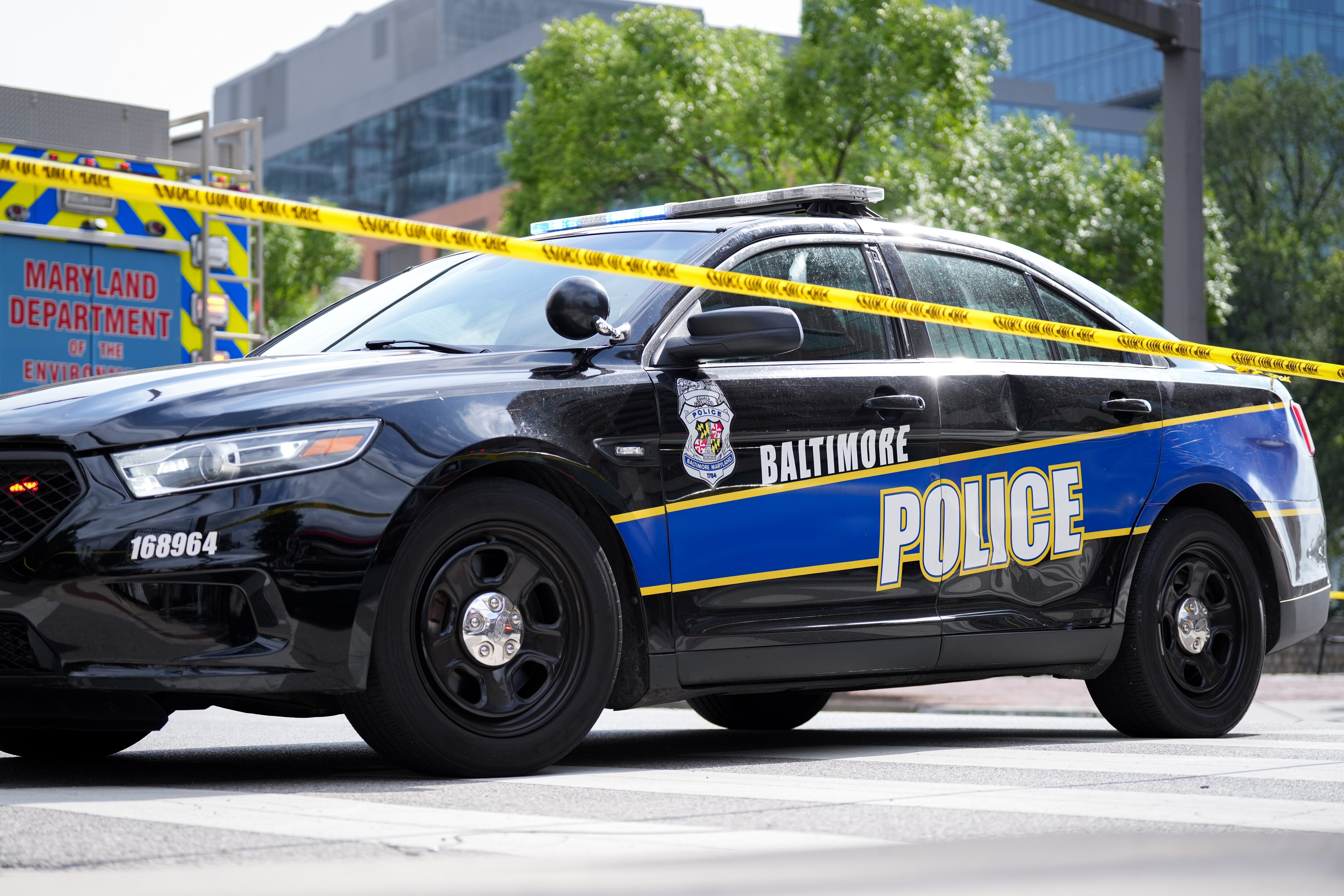 A Baltimore Police car and crime scene tape remains on the scene after a vehicle exploded inside a five-story parking garage in Baltimore’s Fells Point neighborhood on 7/27/22.  Two people are being treated for injuries, fire officials said Wednesday afternoon.