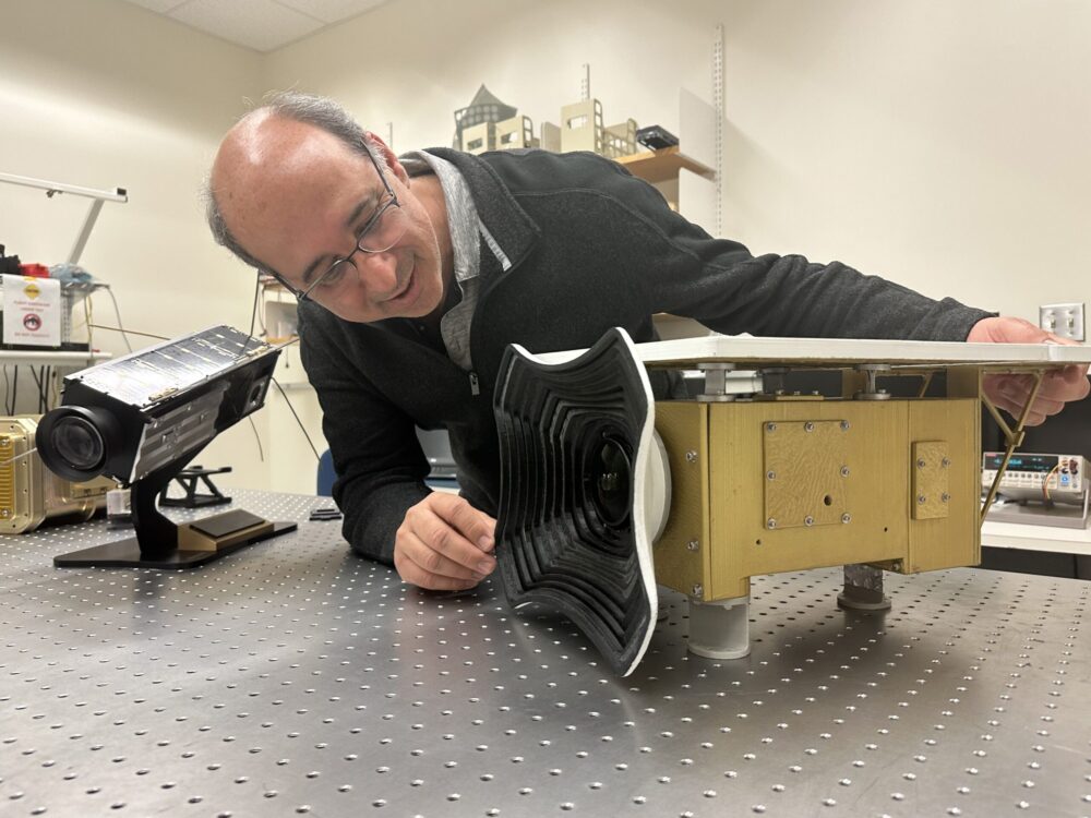 University of Maryland, Baltimore County professor Vanderlei Martins examines a replica of HARP2, an instrument on the PACE satellite that will help identify particles in Earth’s atmosphere.