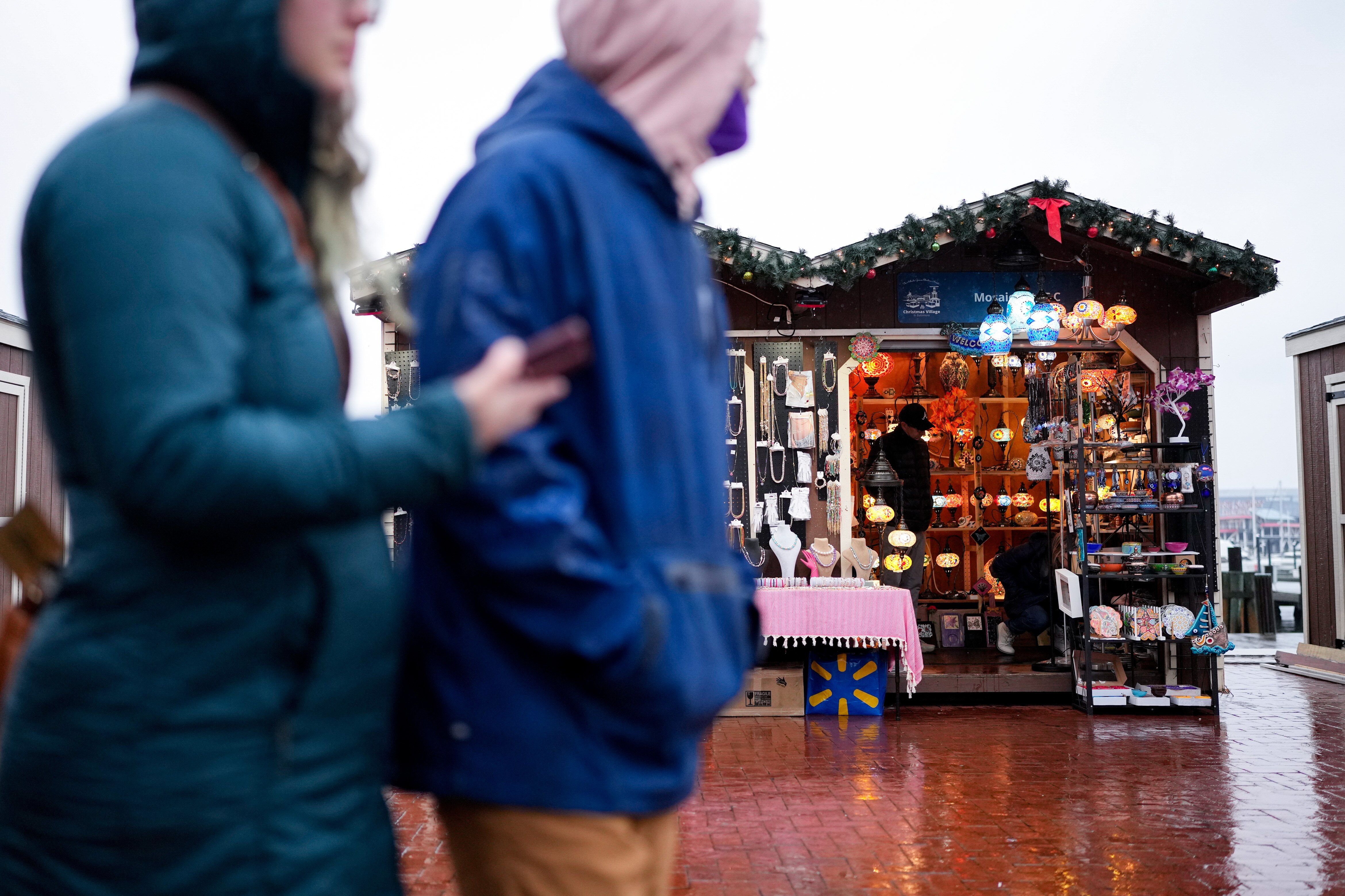 Patrons walk past vendors through the Christmas Village at the Inner Harbor in Baltimore, Md. on Friday, December 20, 2024.