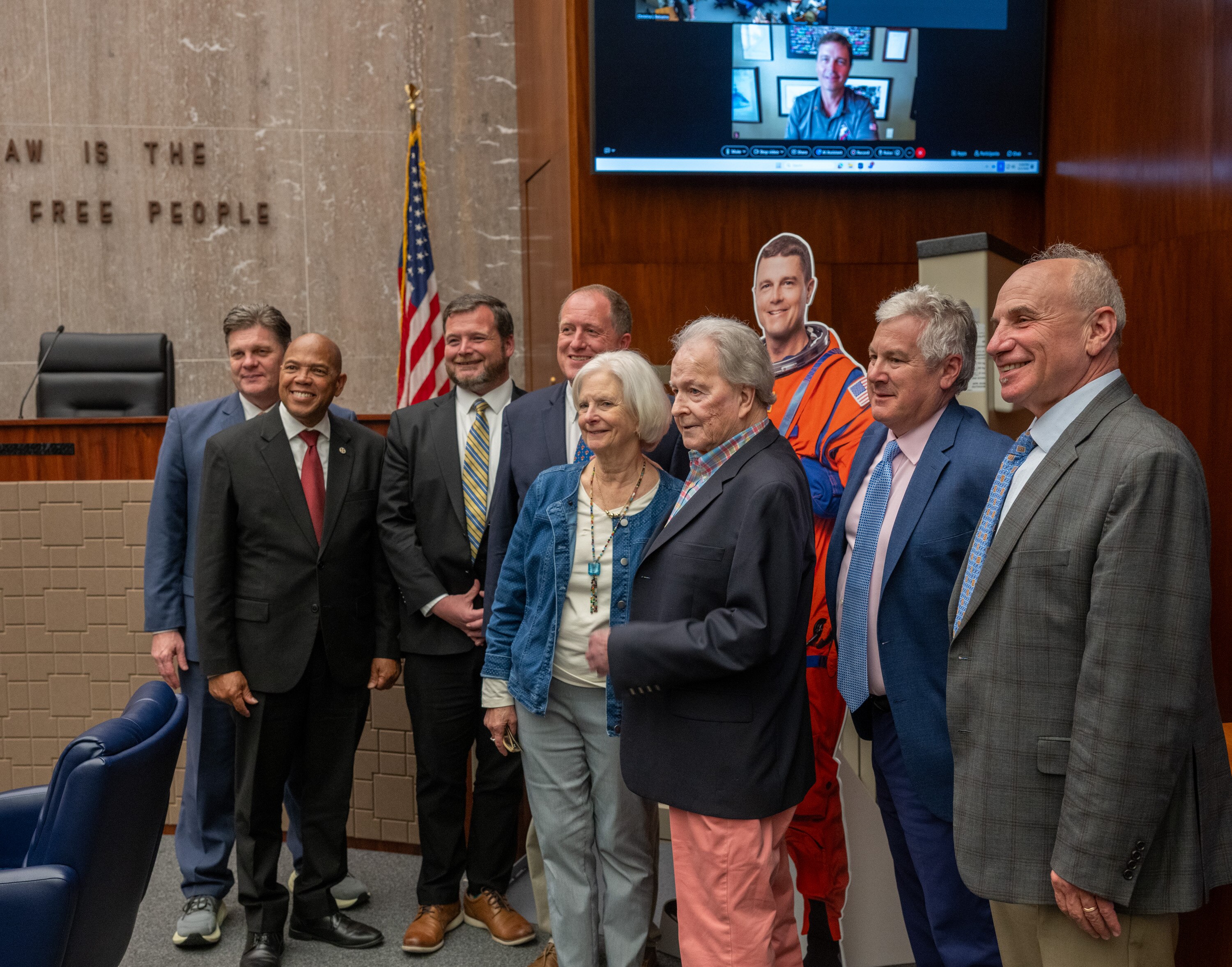 Baltimore County Executive Kathy Klausmeier, center, Bill Wiseman, father of Artemis II commander Reid Wiseman, and council members stand with a life-sized cutout of astronaut Wiseman as he is honored Monday night. Wiseman attended virtually from Houston.