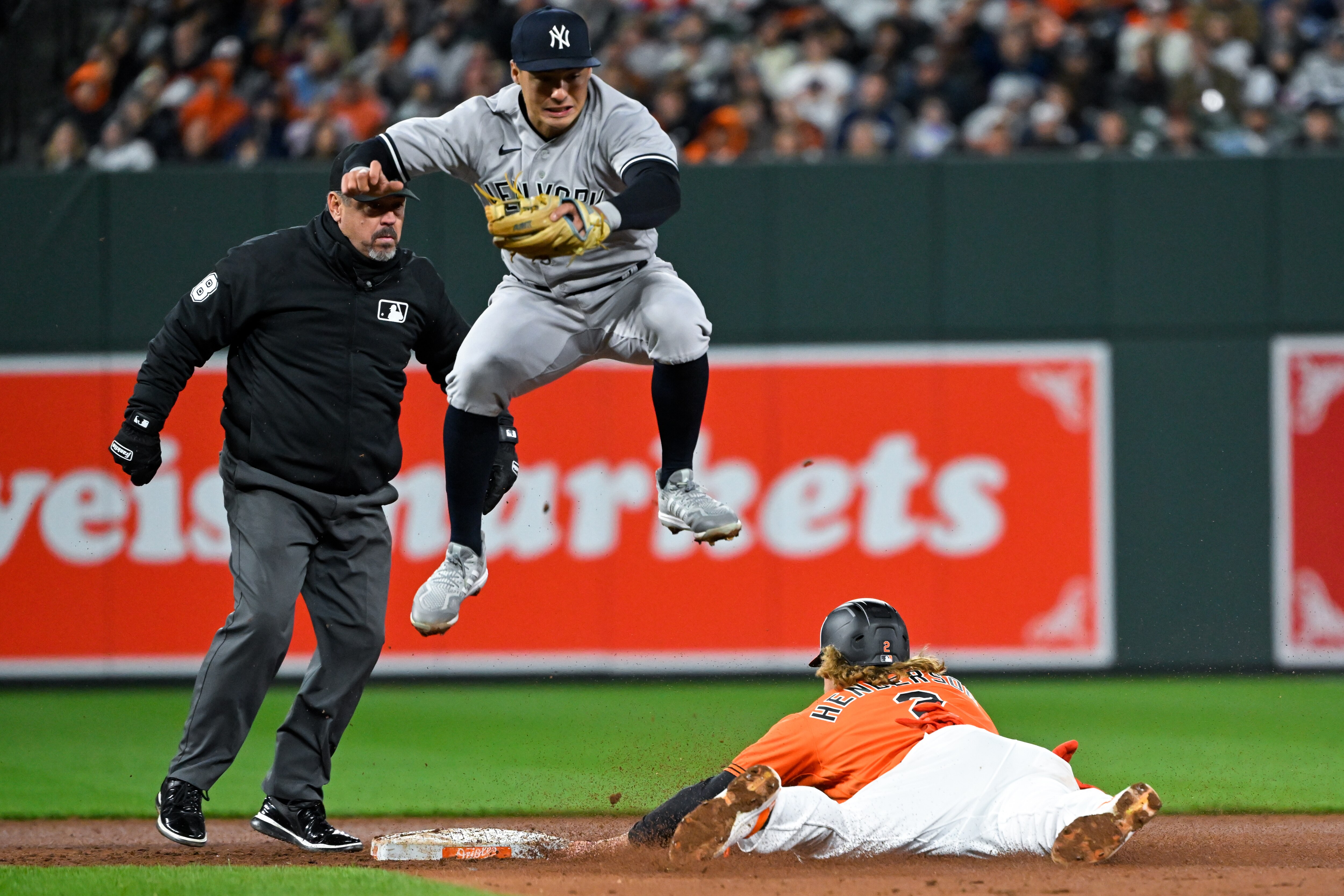 Baltimore Orioles’ Gunnar Henderson (2) steals second base and New York Yankees shortstop Anthony Volpe (11) attempts to catch the errant throw during the fourth inning of an baseball game, Friday, April 7, 2023, in Baltimore.
