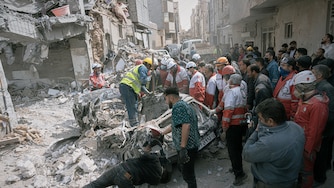 First responders inspect a destroyed car at the site of a residential building hit in an overnight strike in Tabriz, East Azerbaijan Province, northwestern Iran.