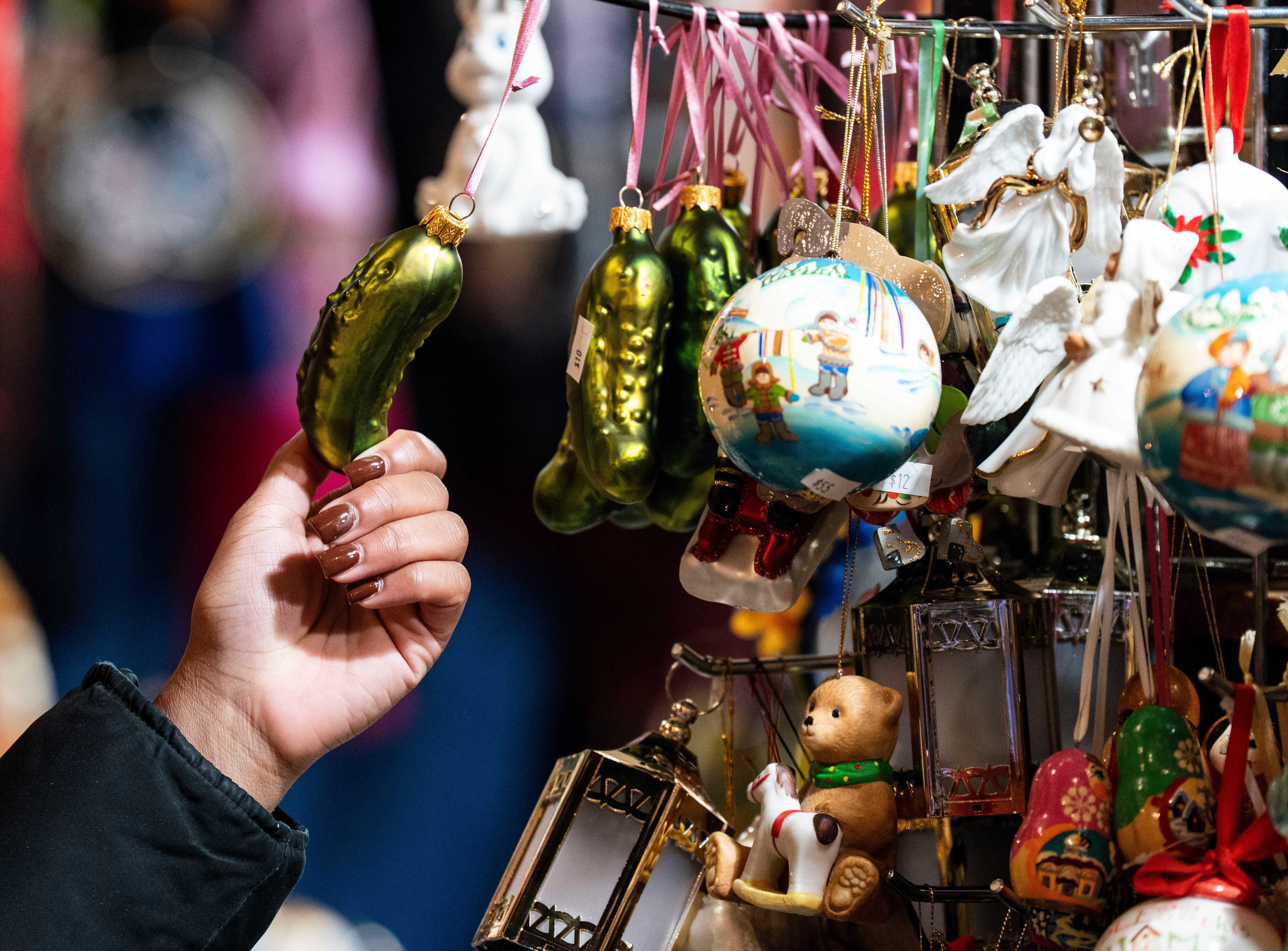Kayla Howard, of Baltimore, looks at a pickle Ornament at Myroslavas Creations at Baltimore’s Christmas Village, Saturday, December 10, 2022.