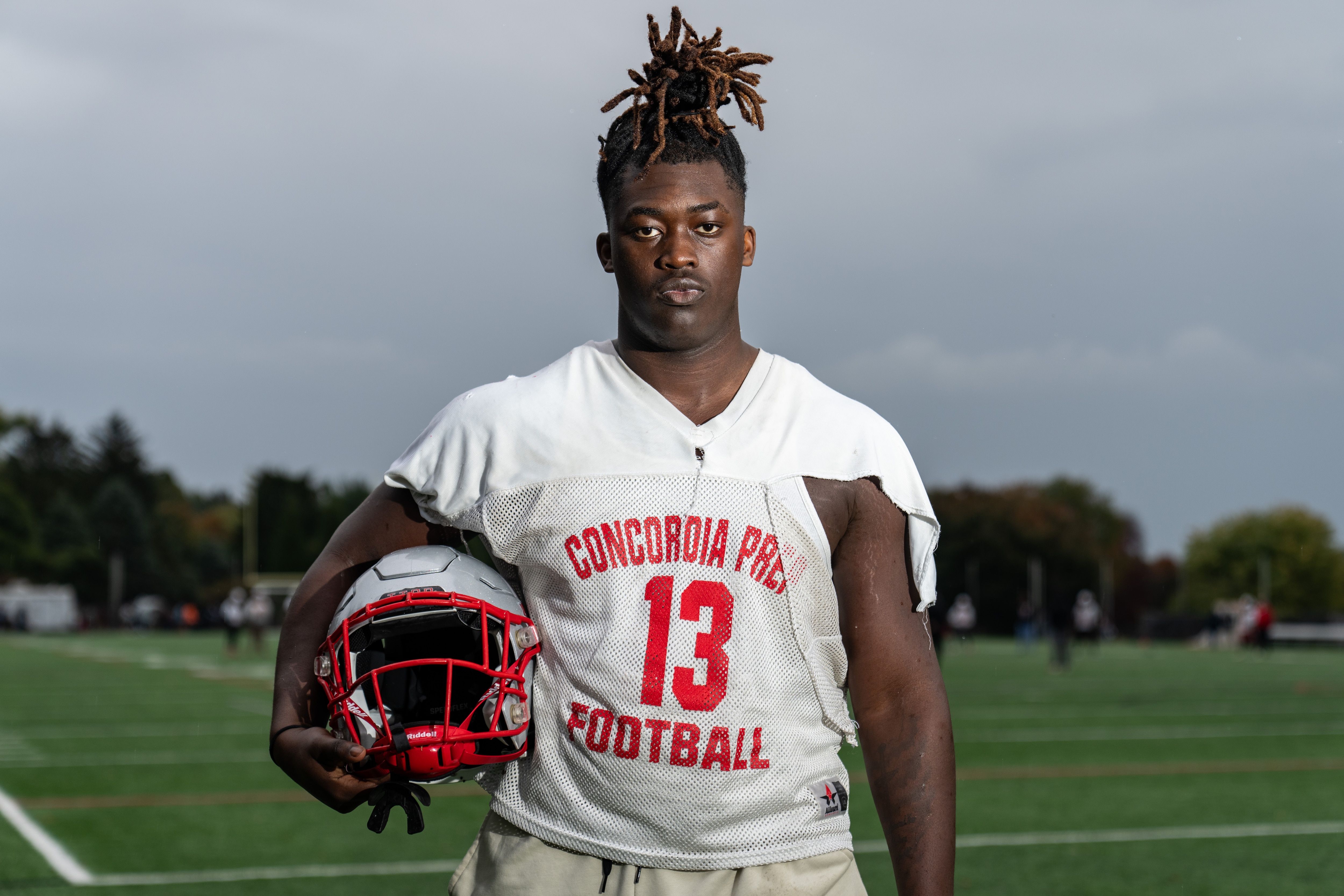 Ernest Willor poses for a portrait at Saints Field holding his helmet.