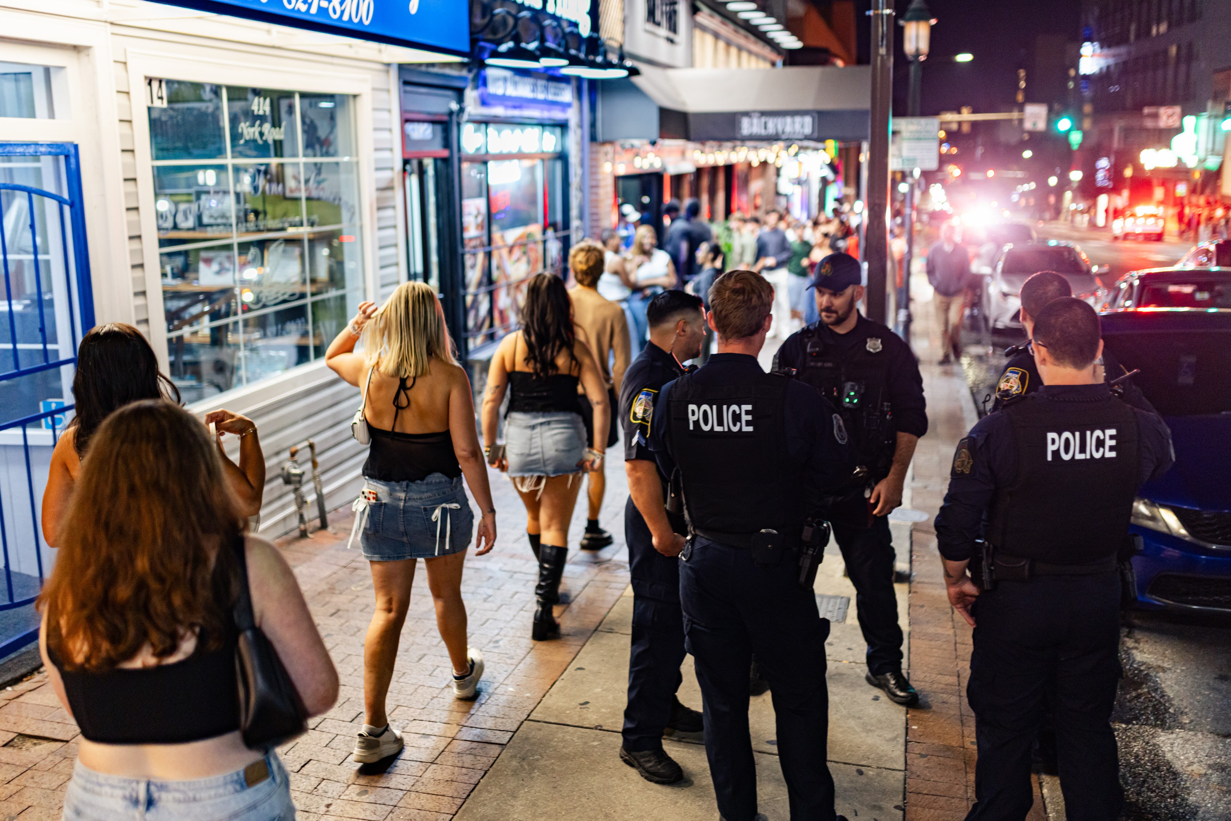Police officers patrol the sidewalk as revelers participate in a recent Thirsty Thursday in Towson.