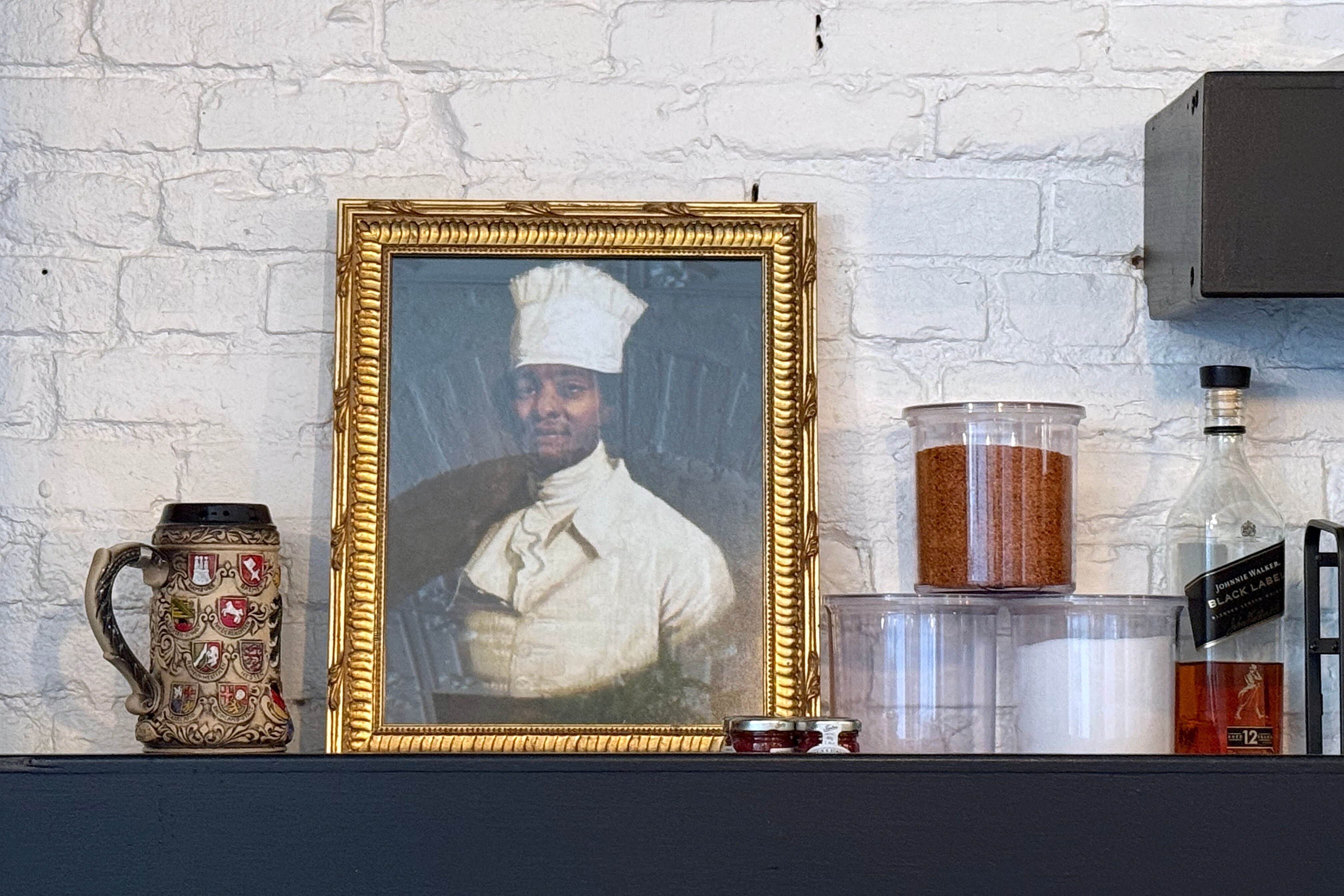 WEDNESDAY, JUNE 24, 2026 - At Rooted Rotisserie in Hollins Market, an 18th century portrait of a Black chef sits by the bar in homage to James Hemings, the formerly enslaved, classically trained chef who worked in Baltimore as a free man.