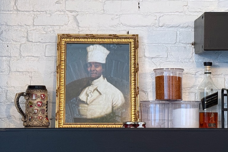 WEDNESDAY, JUNE 24, 2026 - At Rooted Rotisserie in Hollins Market, an 18th century portrait of a Black chef sits by the bar in homage to James Hemings, the formerly enslaved, classically trained chef who worked in Baltimore as a free man.