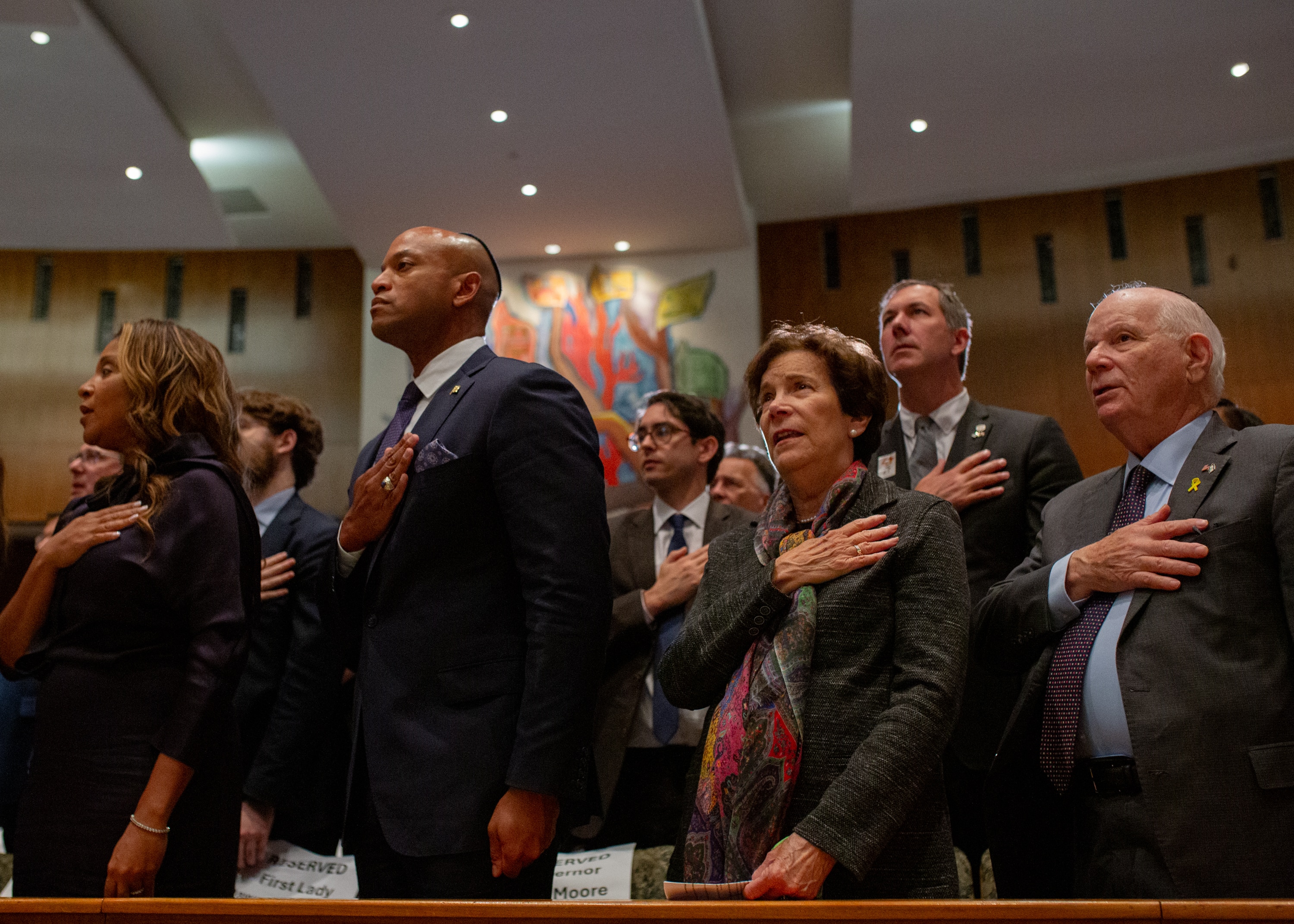 Gov. Wes Moore, Sen. Ben Cardin, County Executive John Olszewski Jr., and others stand for the National Anthem at the October 7 Baltimore Community Commemoration event at Beth El Congregation in Pikesville, Md.