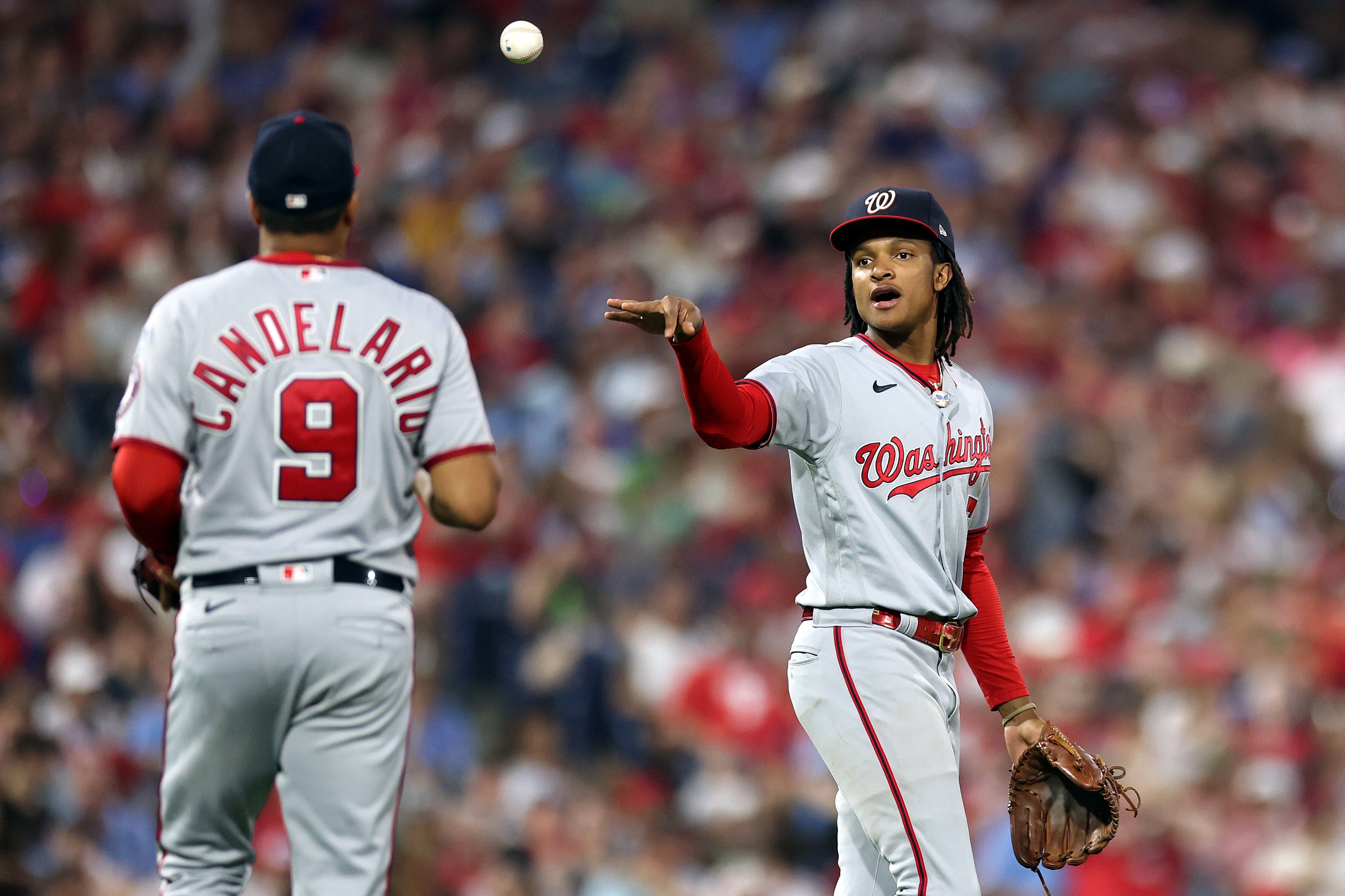 The Nationals' CJ Abrams tosses the ball to Jeimer Candelario during the ninth inning of Washington's 2-1 win at Philadelphia on Friday night.