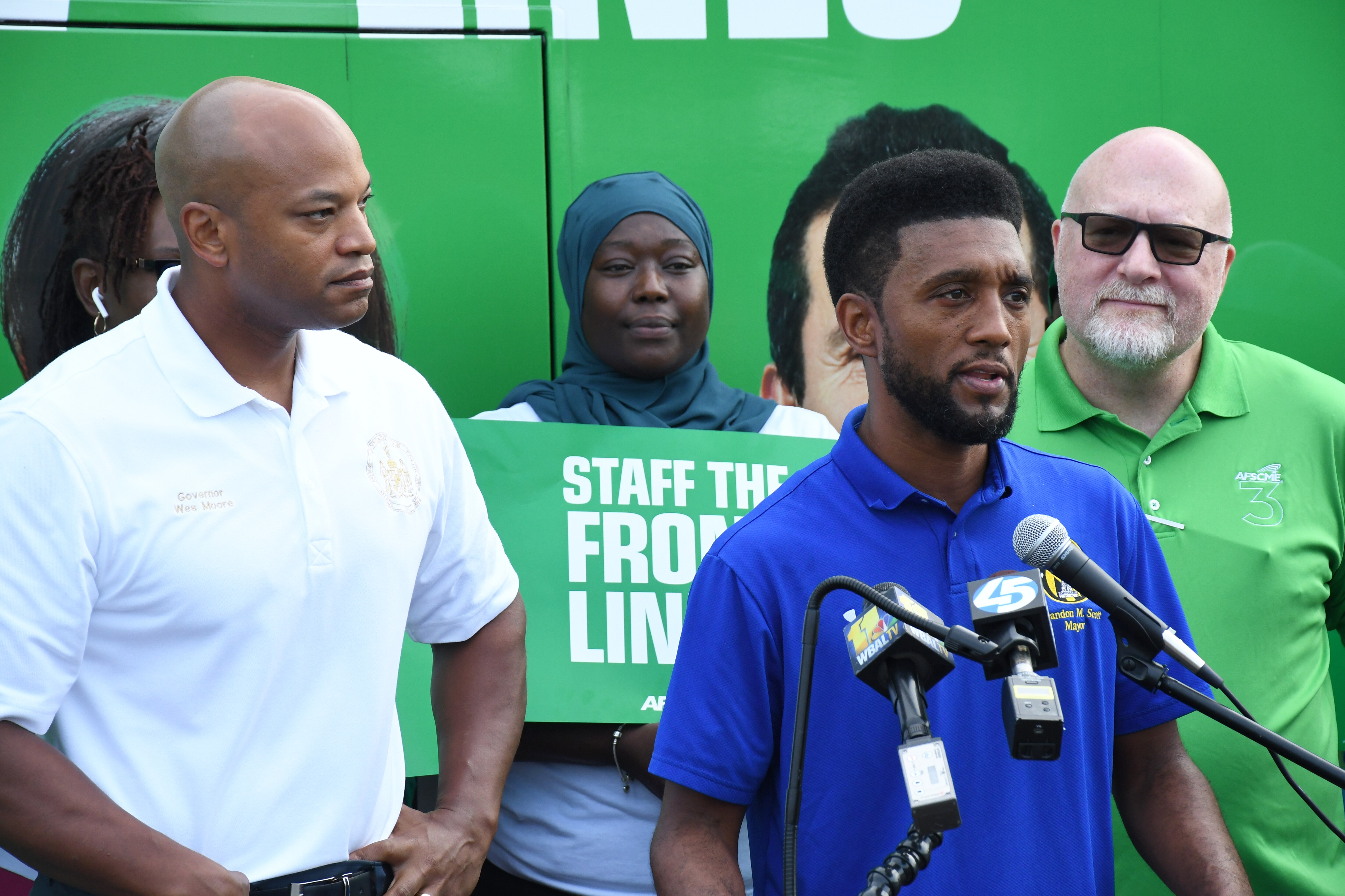 Baltimore Mayor Brandon Scott speaks at a "staff the front lines" event with members of the AFSCME union outside the union building in southwest Baltimore on Saturday, Sept. 9, 2023. Standing beside him are Gov. Wes Moore, at left, and AFSCME Maryland Council 3 President Pattrick Moran.