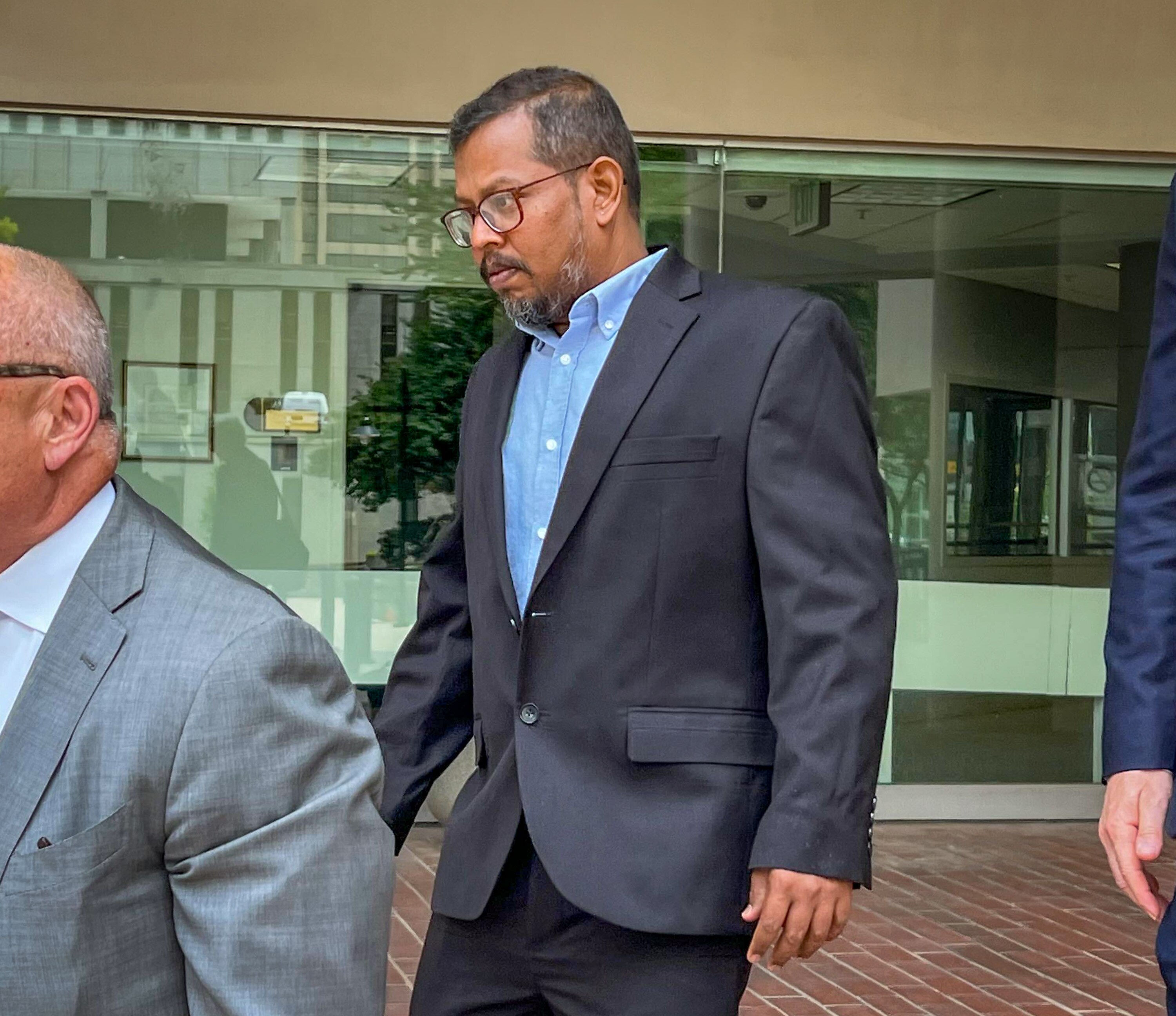 Karthikeyan Deenadayalan, center, the chief engineer of the Dali cargo ship, leaves a federal courthouse earlier this year after a hearing in which he entered into a deferred prosecution agreement on a felony charge related to the Key Bridge disaster.