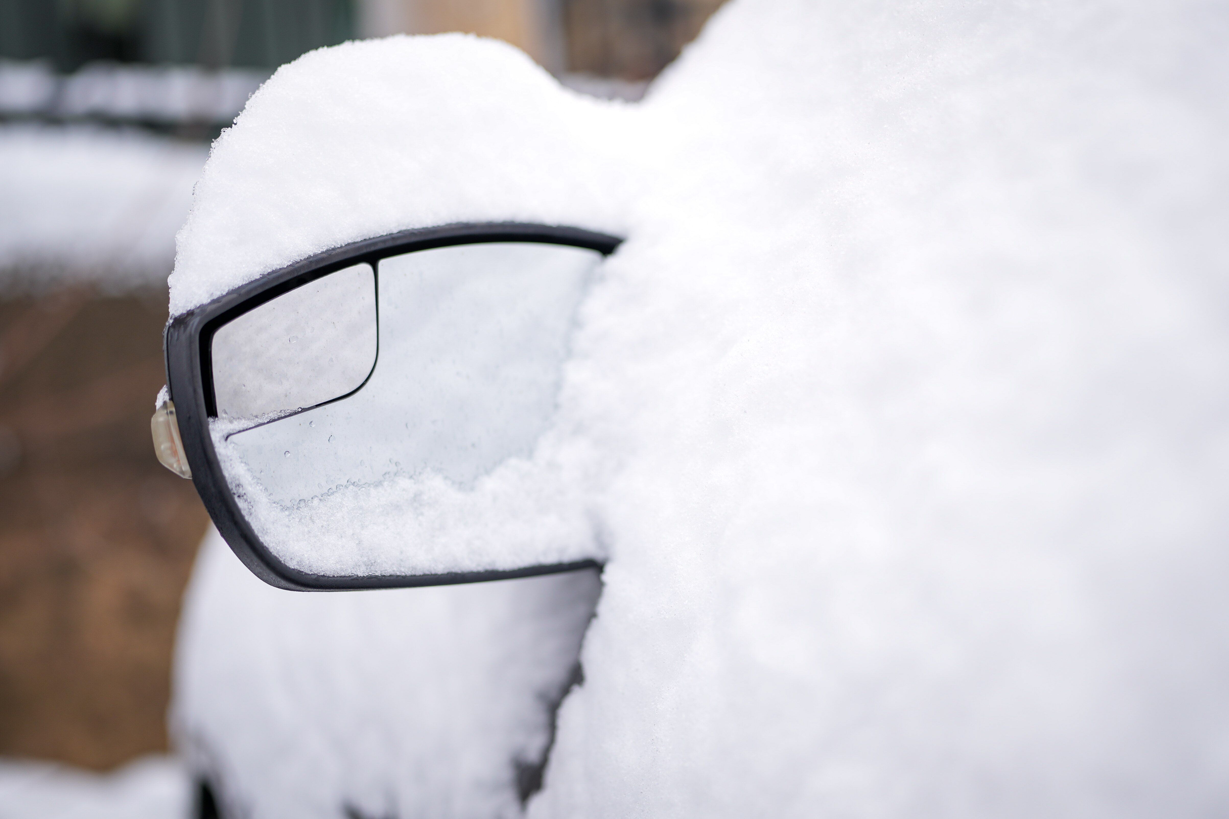 A frozen side-view mirror on a snow-covered car in Charles Village on Jan. 16, 2024.