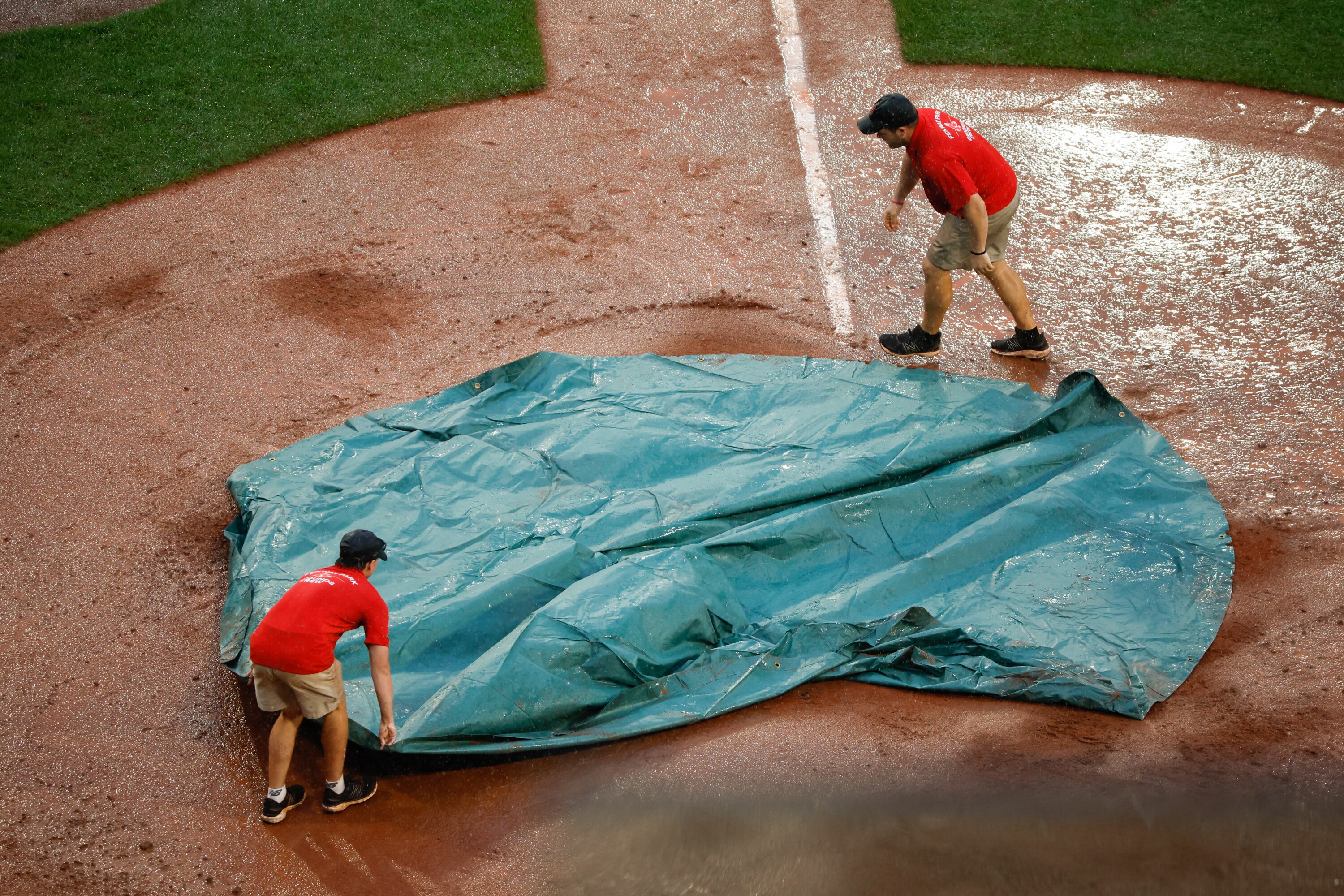 BOSTON, MASSACHUSETTS - SEPTEMBER 10: Members of the Fenway Park Grounds Crew pull the tarp across home plate during a rain delay in the eighth inning of a game between the Boston Red Sox and the Baltimore Orioles at Fenway Park on September 10, 2023 in Boston, Massachusetts. (Photo by Rich Gagnon/Getty Images)