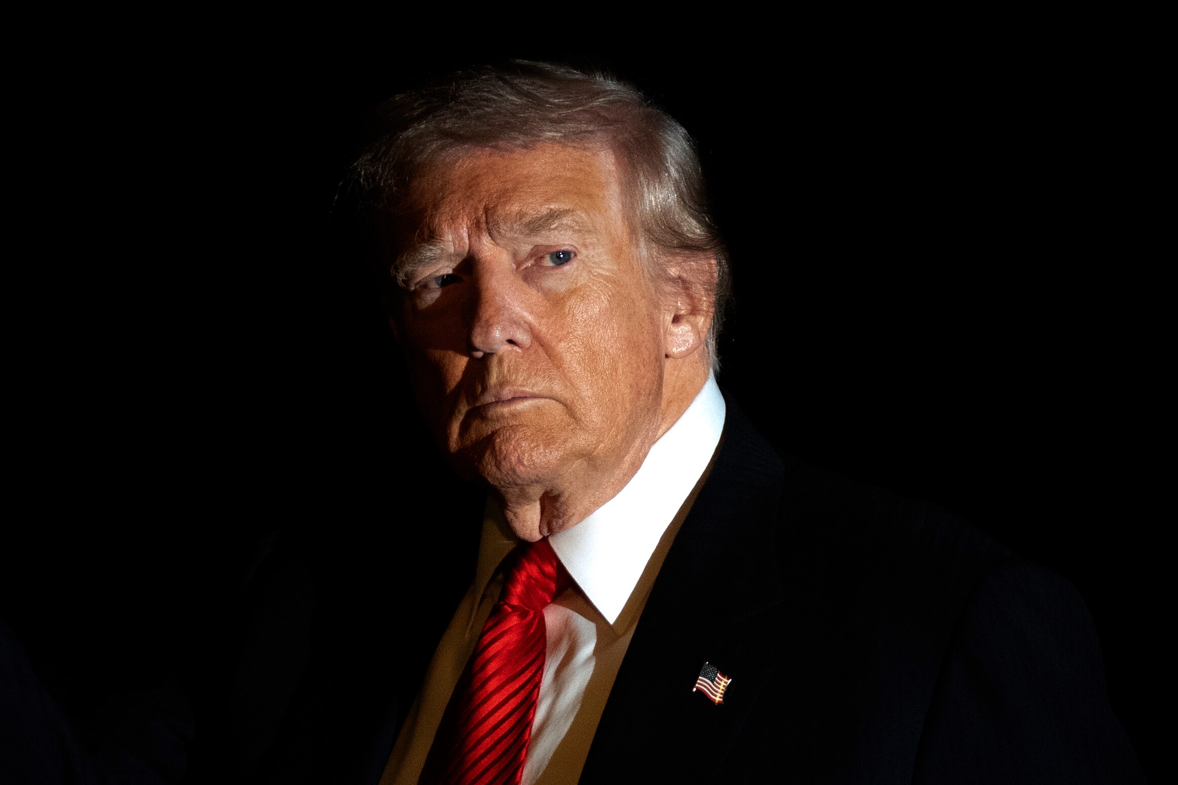 President Donald Trump is illuminated by a camera flash as he gestures while walking across the South Lawn of the White House, Sunday, Nov. 2, 2025, in Washington, after returning from a trip to Florida.