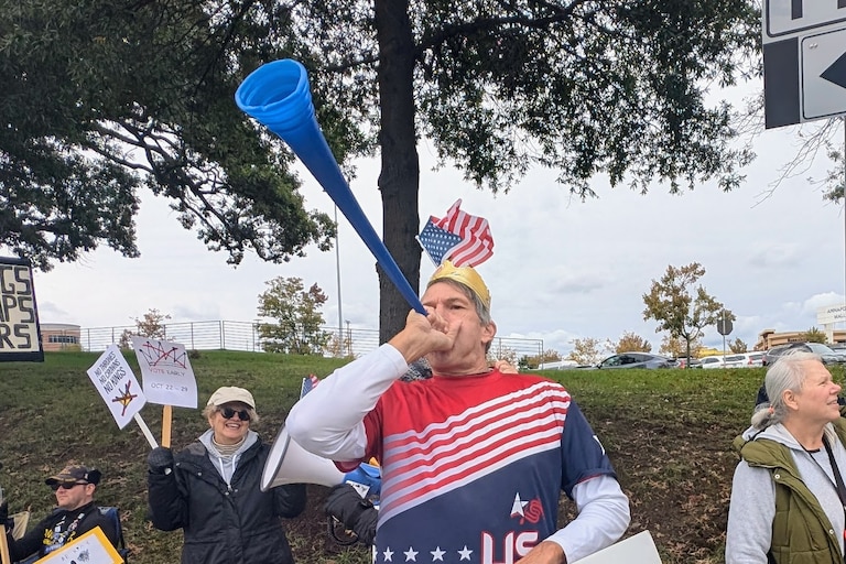 Paul Flack blows his vuvuzela at the Annapolis No Kings rally on Saturday, dressed in American flag colors and topped with a golden Burger King crown. About 600 people turned out for the final rally before Election Day.