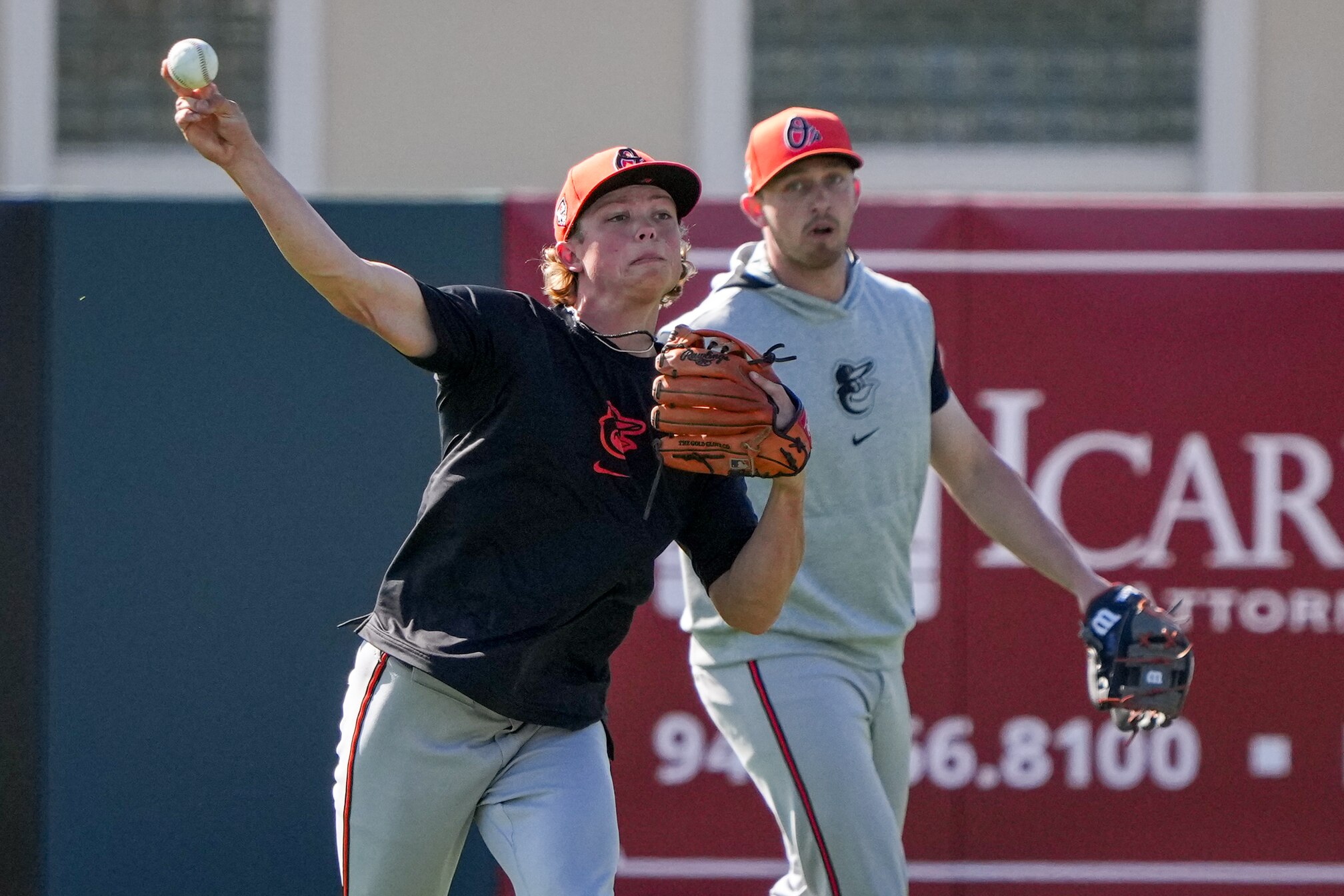 Jackson Holliday throws as Jordan Westburg waits his turn during spring training in Sarasota, Florida.