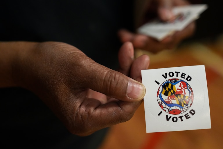An election judge displays an “I voted” sticker on Election Day, Nov. 8, 2022, at Margaret Brent Elementary/Middle School. Polling locations for the general election remain open until 8 p.m.